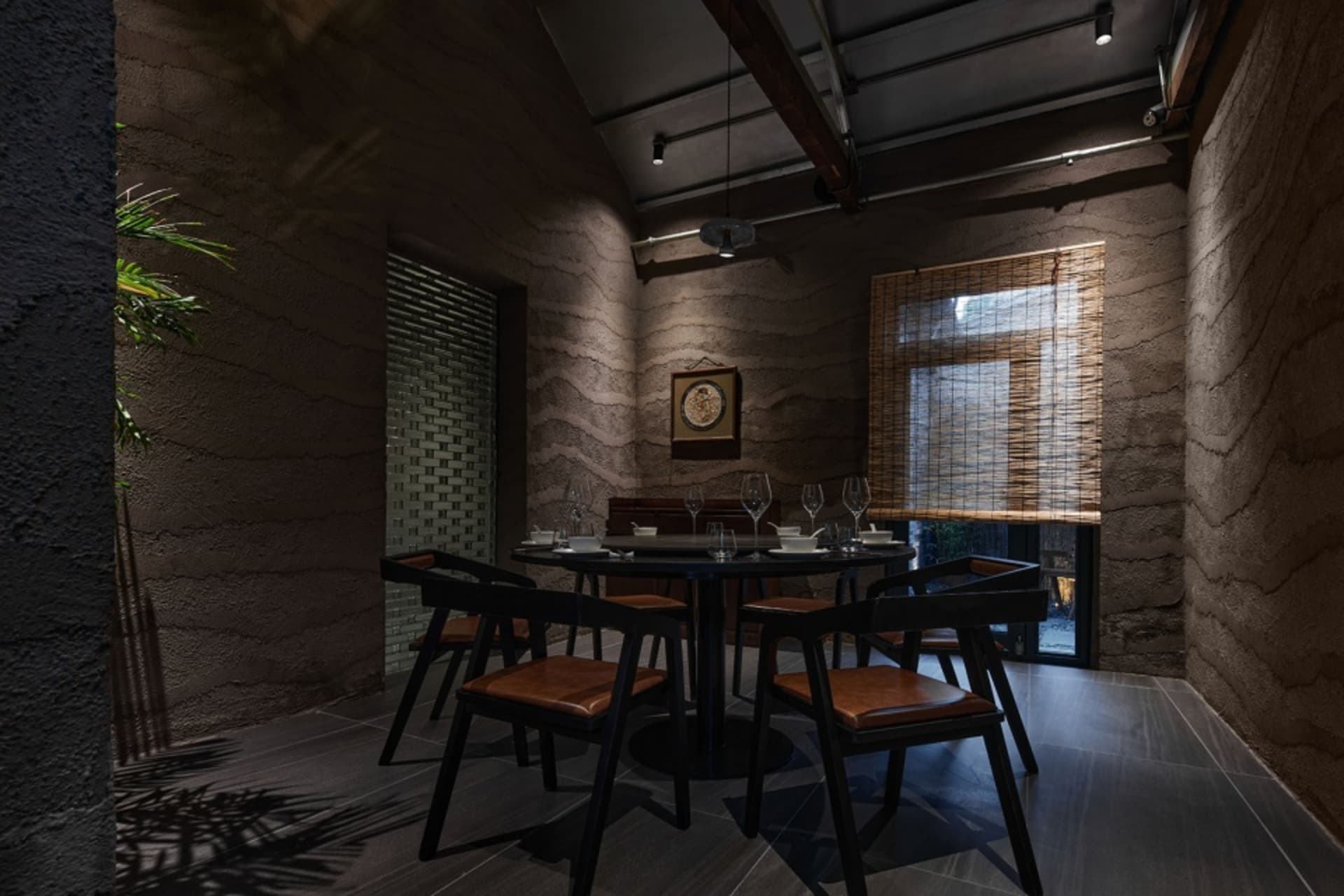 工業風餐廳室內，混凝土牆面搭配木質餐椅與圓形餐桌。