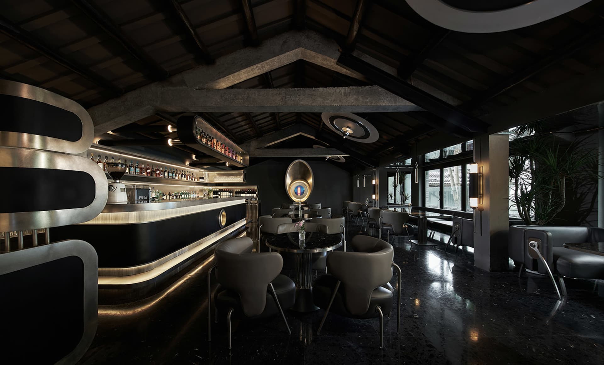 A modern industrial coffee shop bar with a sleek black design, featuring metal and concrete materials, and large windows with