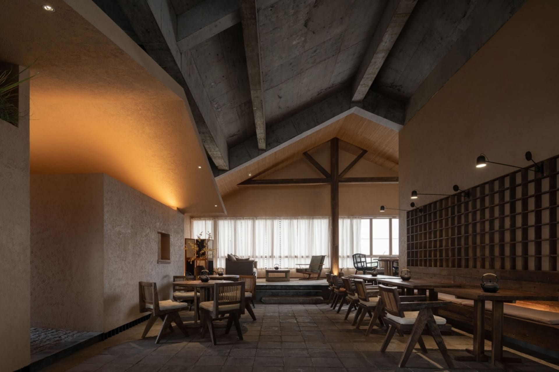Industrial-themed restaurant interior with exposed concrete walls and ceiling beams.