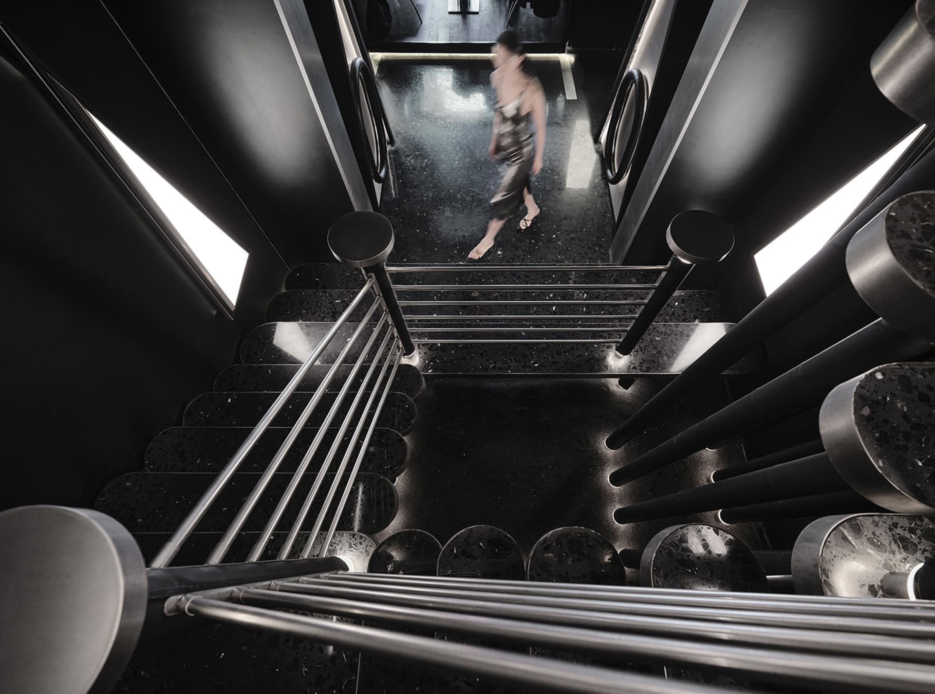 A modern, black metal staircase with a polished stone floor.