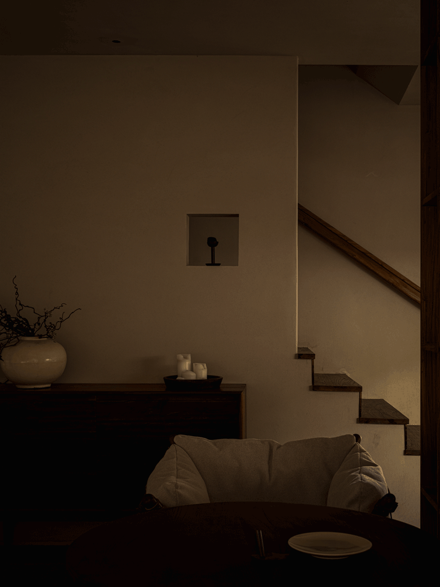 Interior view of a modern living room with dim lighting and a lit candle on a wooden table.
