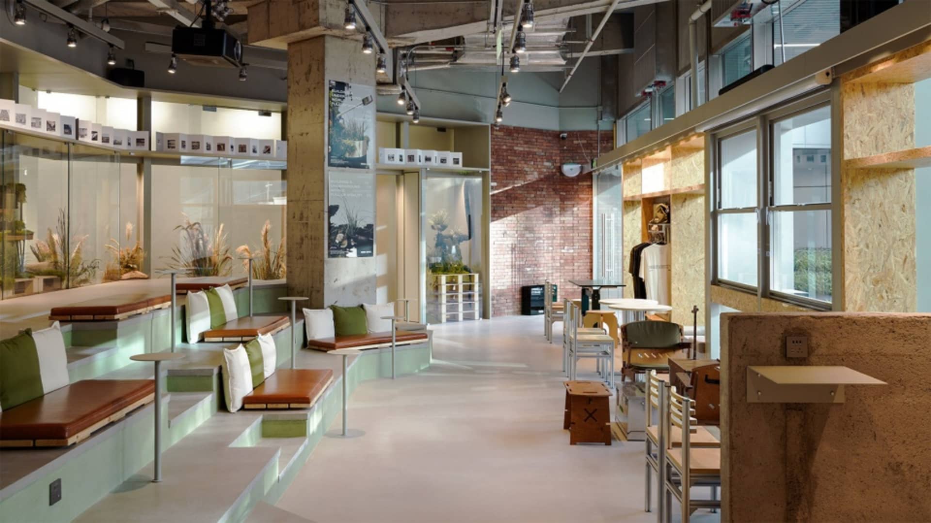 A modern cafe with exposed brick walls and concrete floor, featuring seating areas and tables.