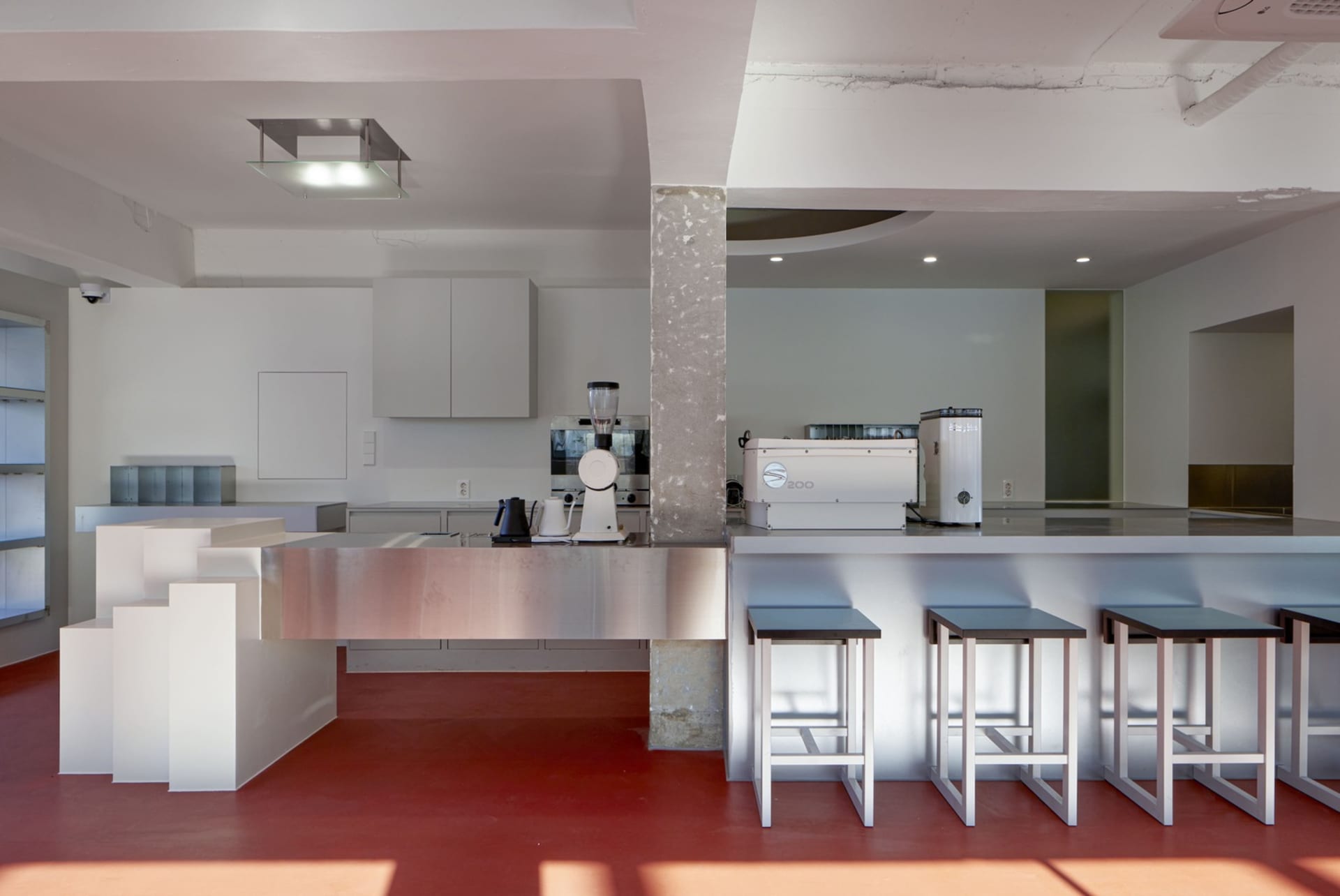 Industrial-style coffee shop with concrete countertops, minimalist decor, and modern furnishings.