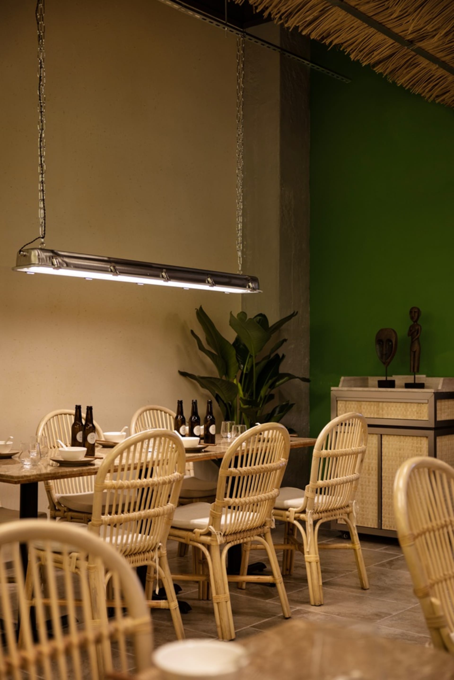 Indoor restaurant dining area with wicker furniture and industrial lighting.