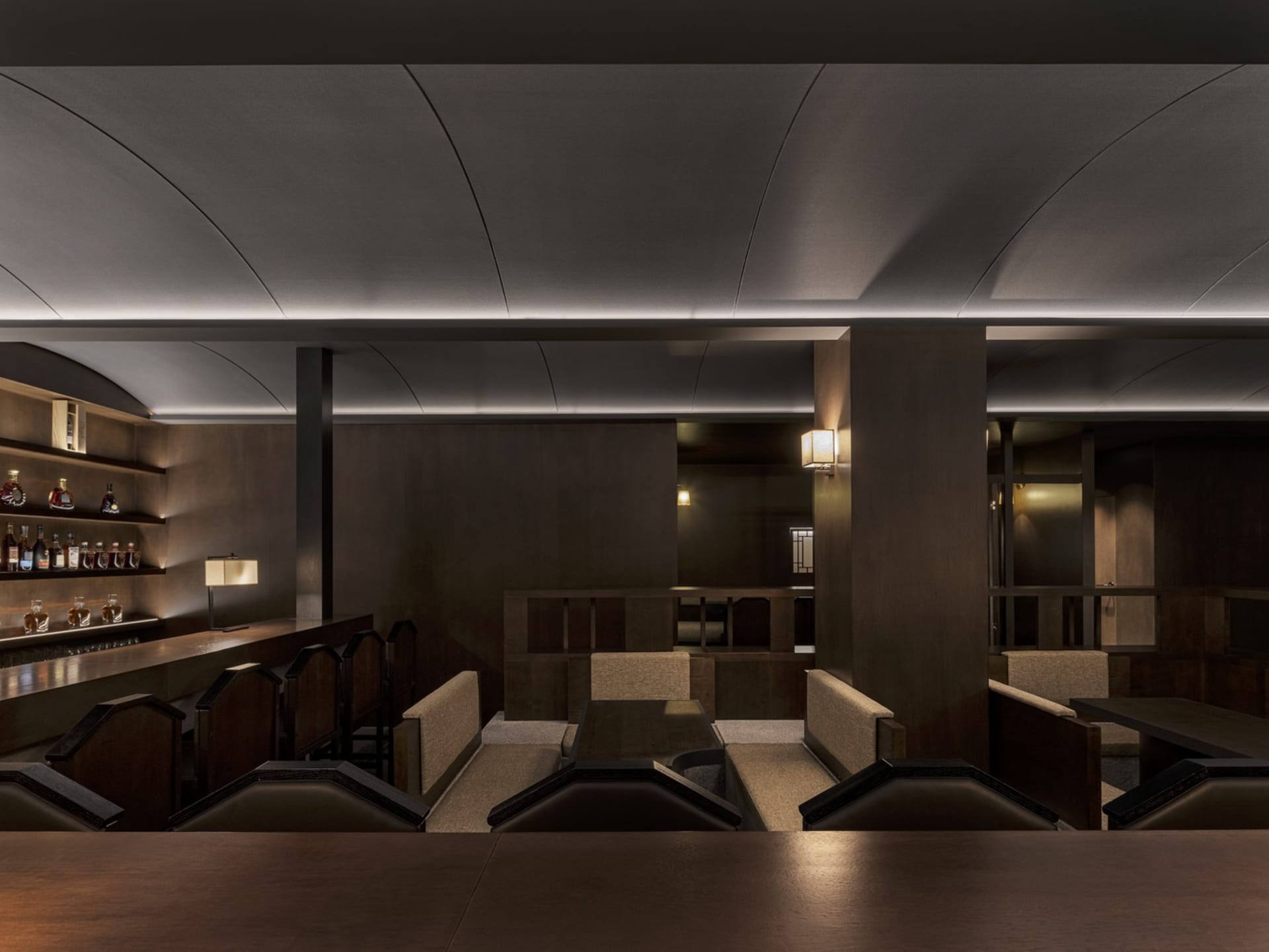 A modern restaurant bar with dark wood and high gloss surfaces.