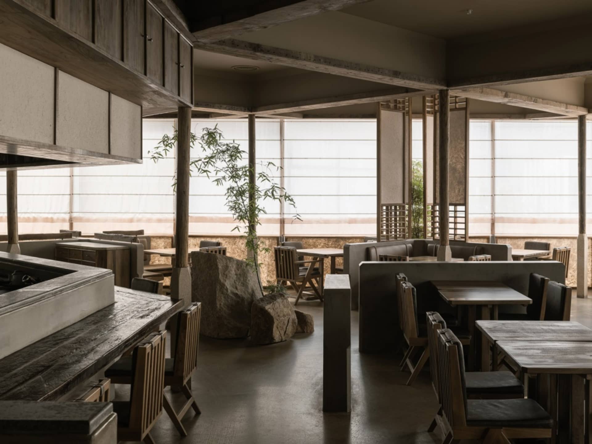 A modern restaurant with wooden tables, stone accents, and large windows