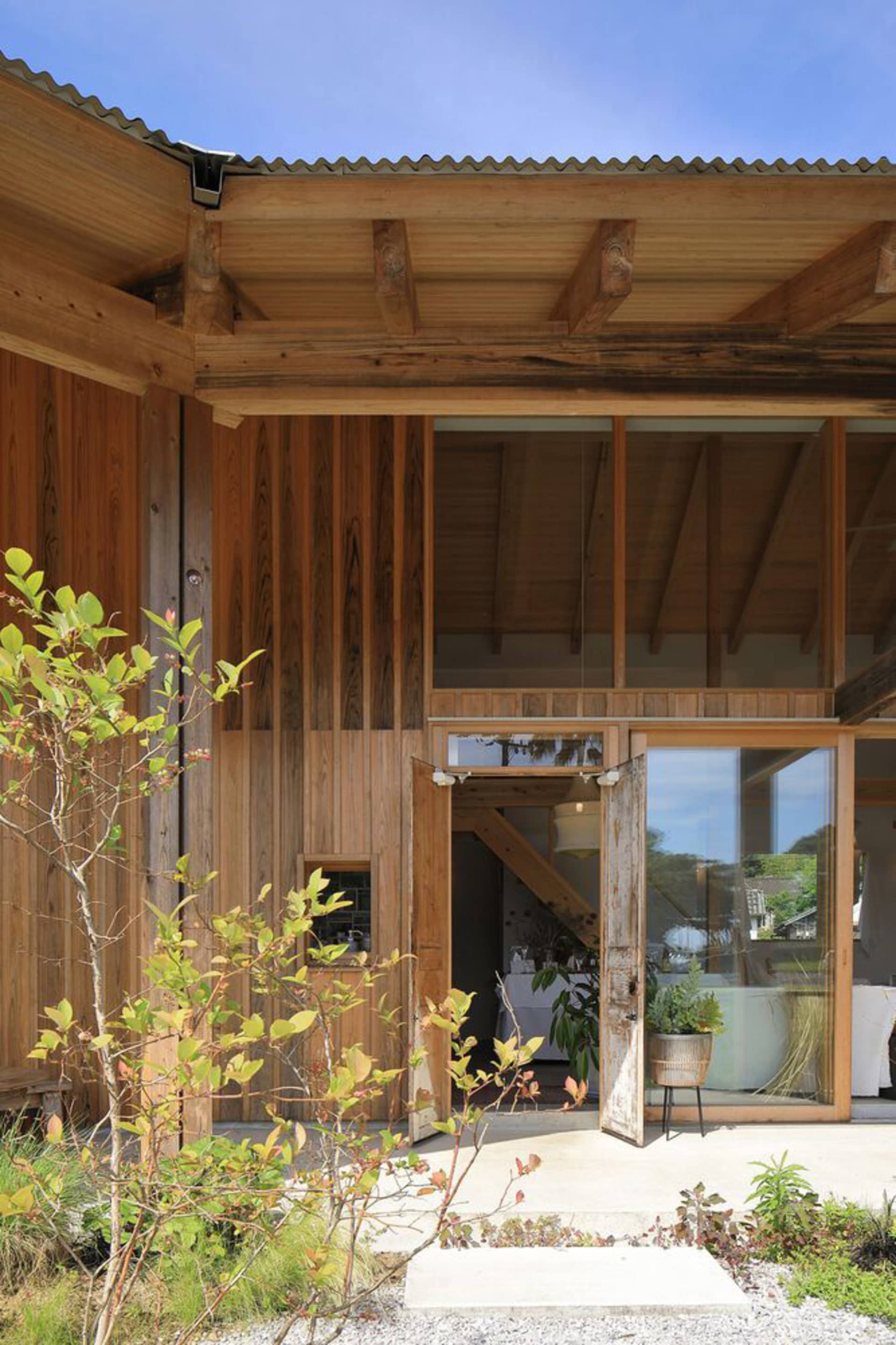 The exterior of a modern, industrial-style house with wooden walls and a corrugated metal roof.