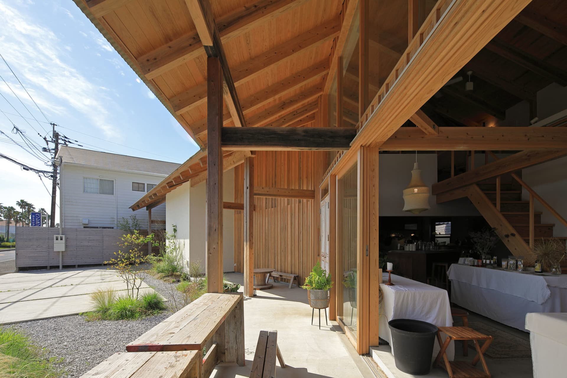 A photograph of a modern restaurant's exterior featuring a wooden structure with high ceilings and large windows.