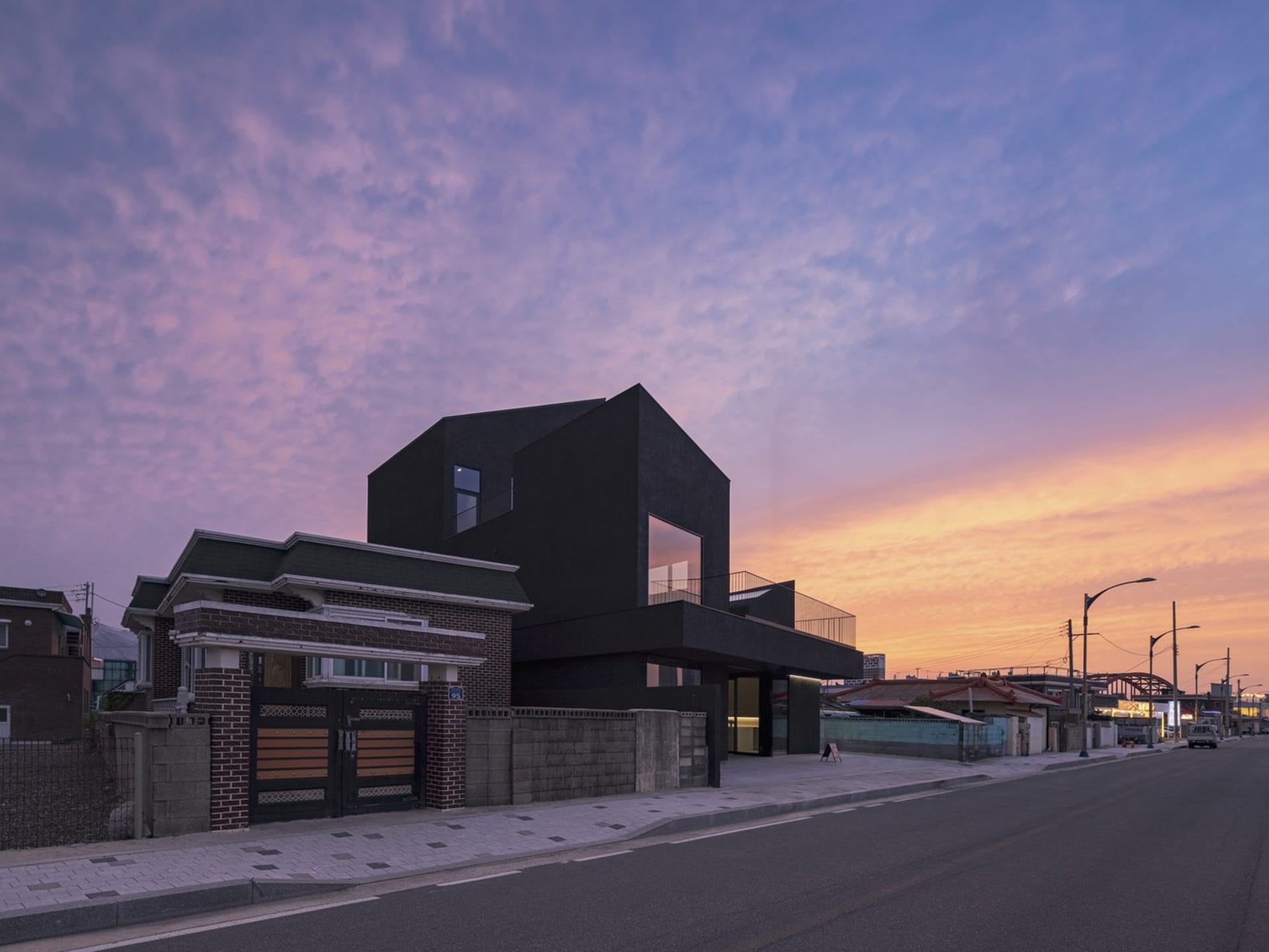A modern black house with a glass facade at sunset