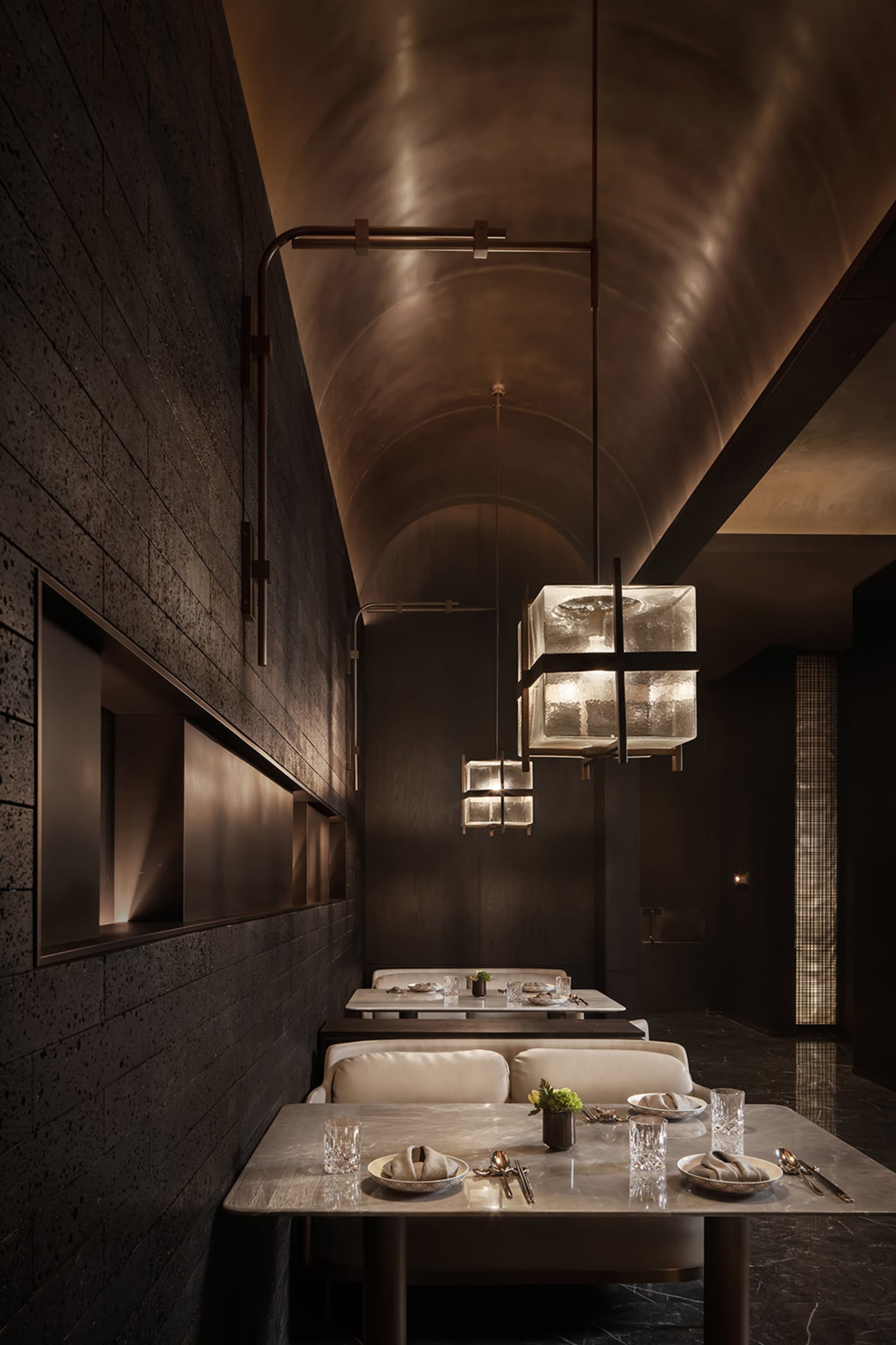 A restaurant interior featuring industrial design elements with dark concrete walls and a dark tile floor.