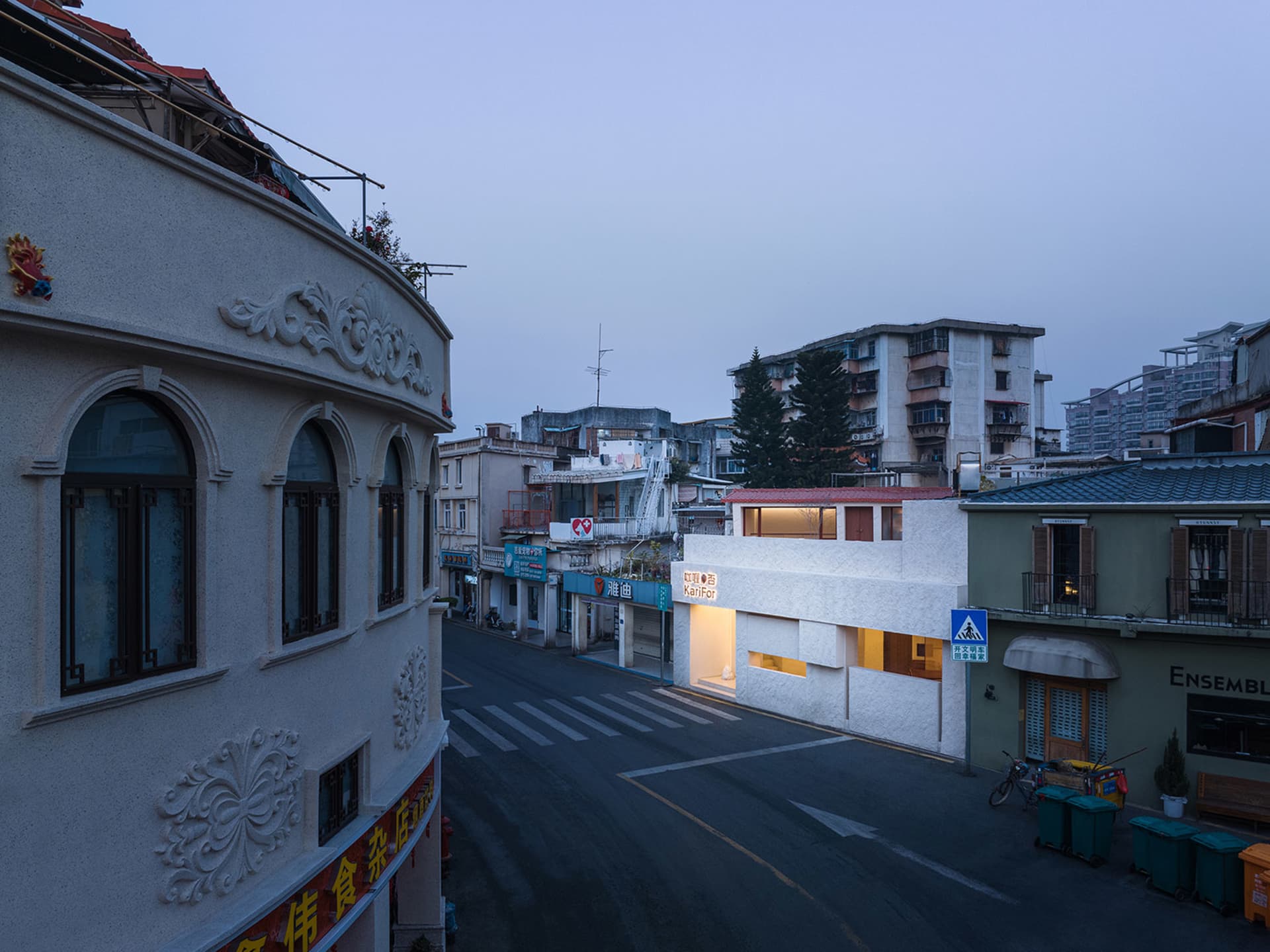 An evening view of an urban street with buildings and storefronts.