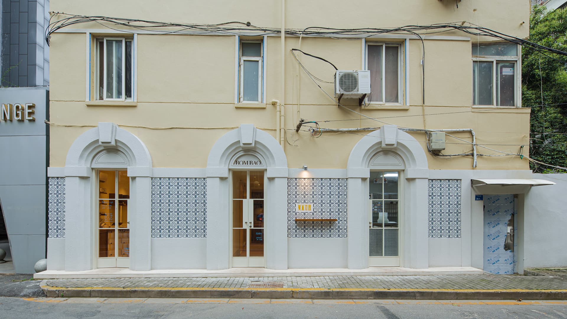 A retail shop front with tiles, concrete, and an air conditioner.