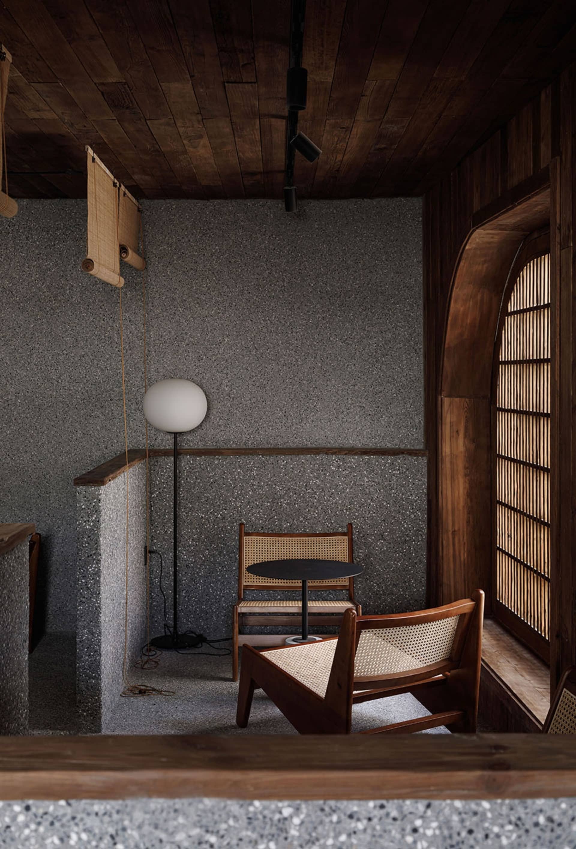 Industrial-style cafe featuring concrete walls, wooden furniture, and a round table with two chairs.