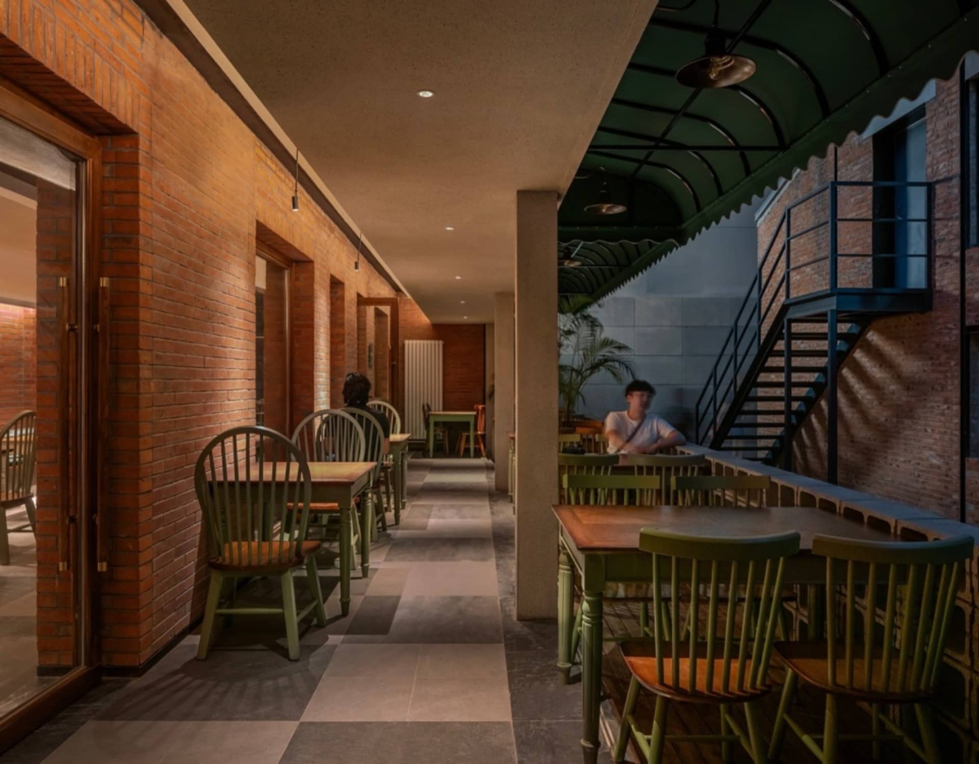 A rustic restaurant interior with exposed brick walls, concrete pillars, and tiled flooring.