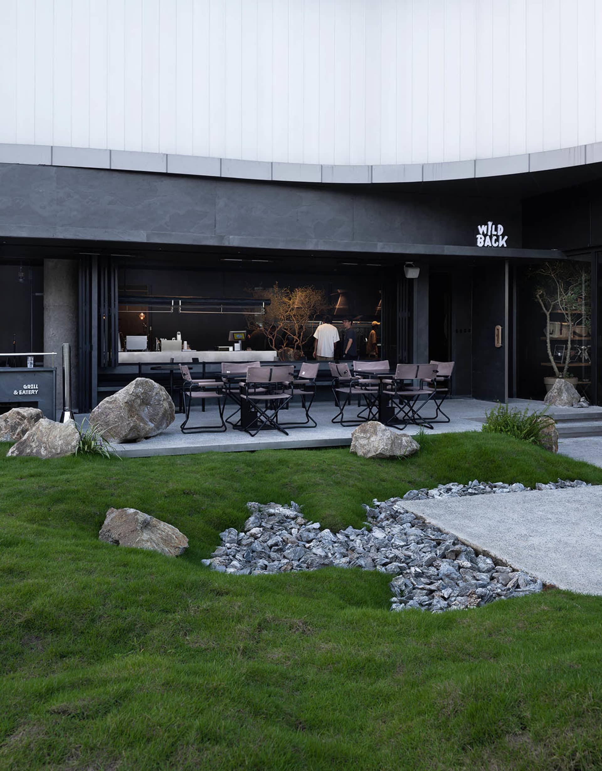 Modern minimalist cafe exterior with concrete and granite elements.