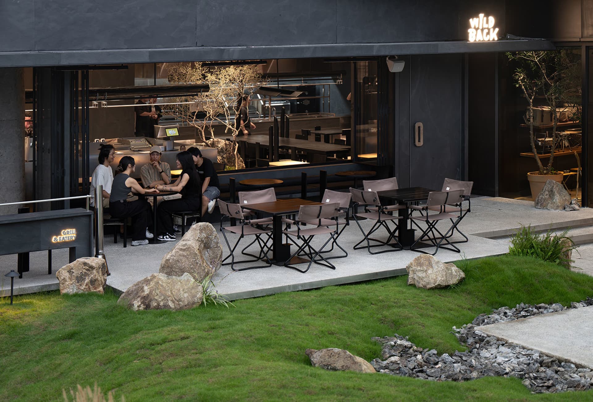 Outdoor seating area of a restaurant with tables and chairs surrounded by greenery.