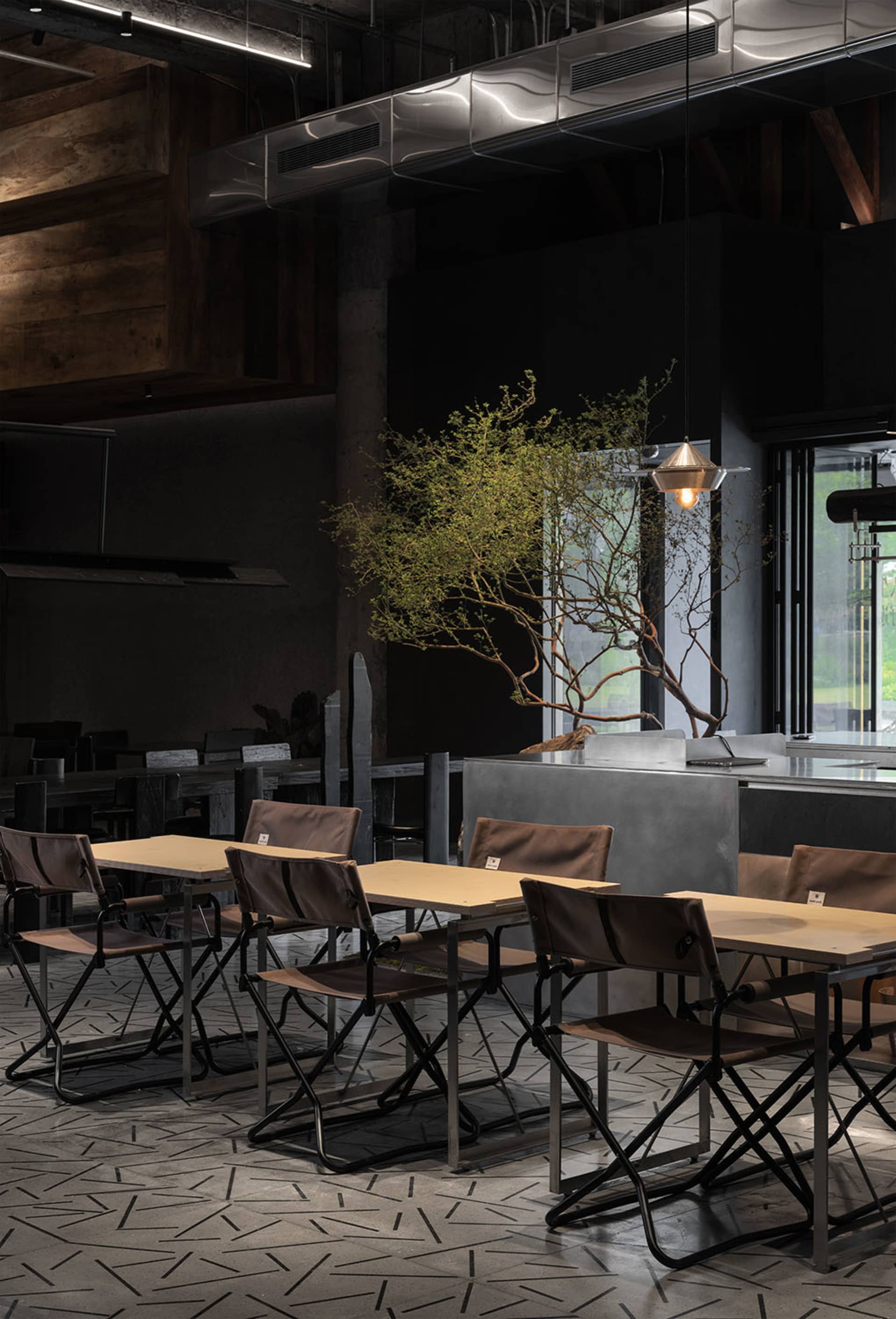 Industrial-style restaurant interior with metal accents, concrete walls, and wooden tables and chairs.
