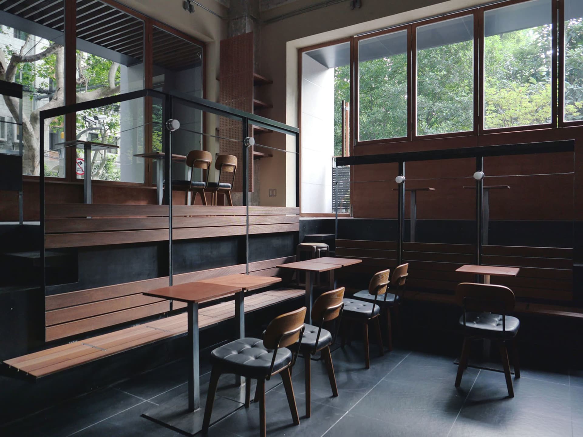 A modern cafe interior with wooden furniture, glass partitions, and metallic accents.