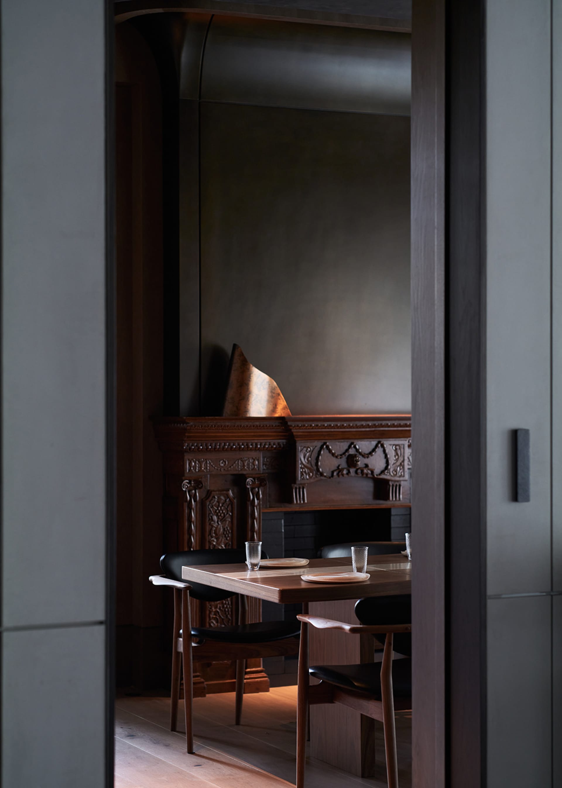 A modern dining room featuring wooden furniture and black leather chairs.