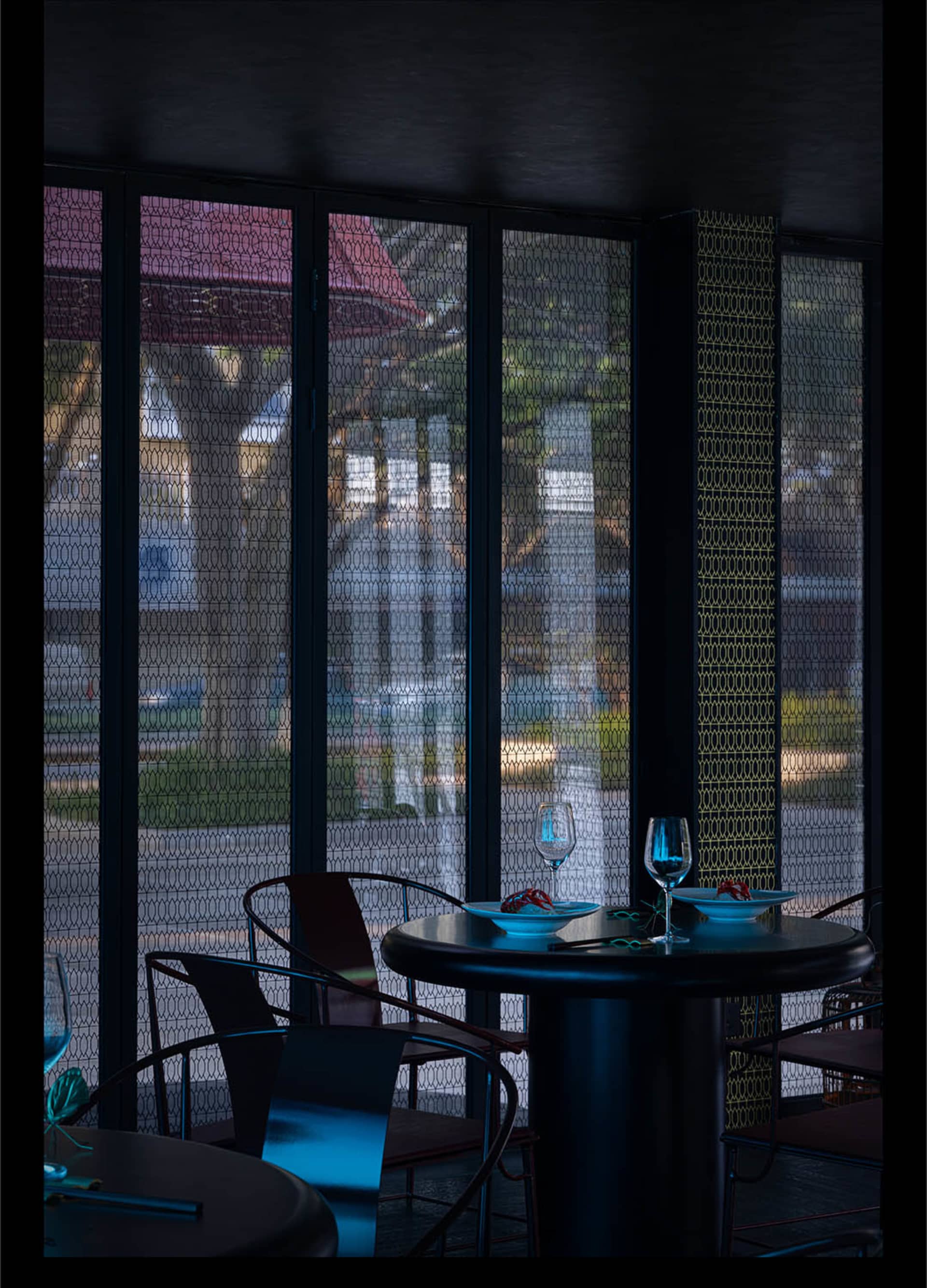 A modern restaurant interior with glass walls, a table, and chairs.