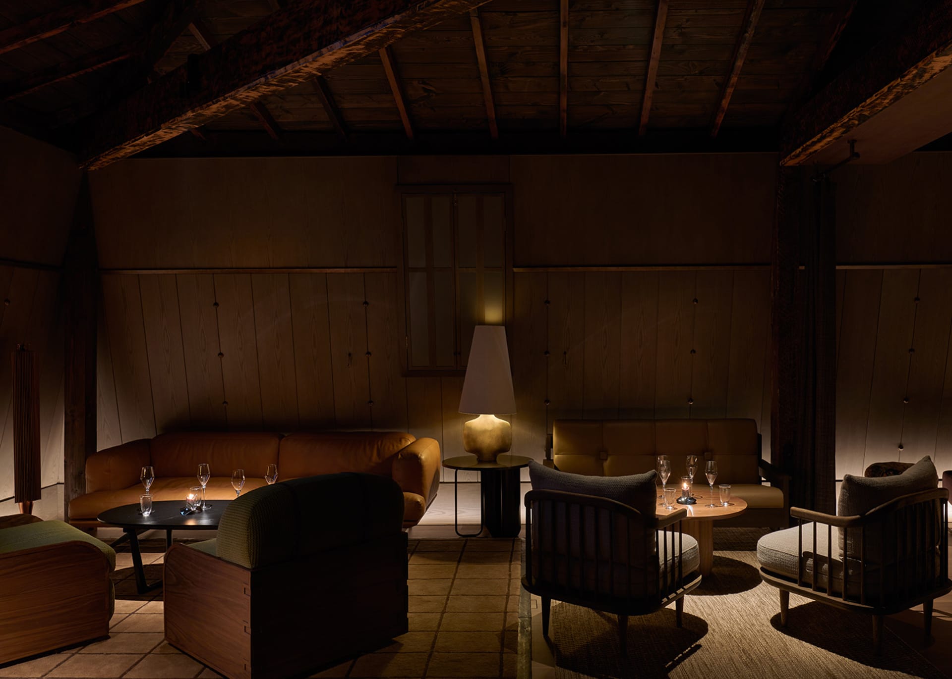 A modern-style living room with dark wooden accents, leather sofas, and a cozy ambiance created by warm lighting.