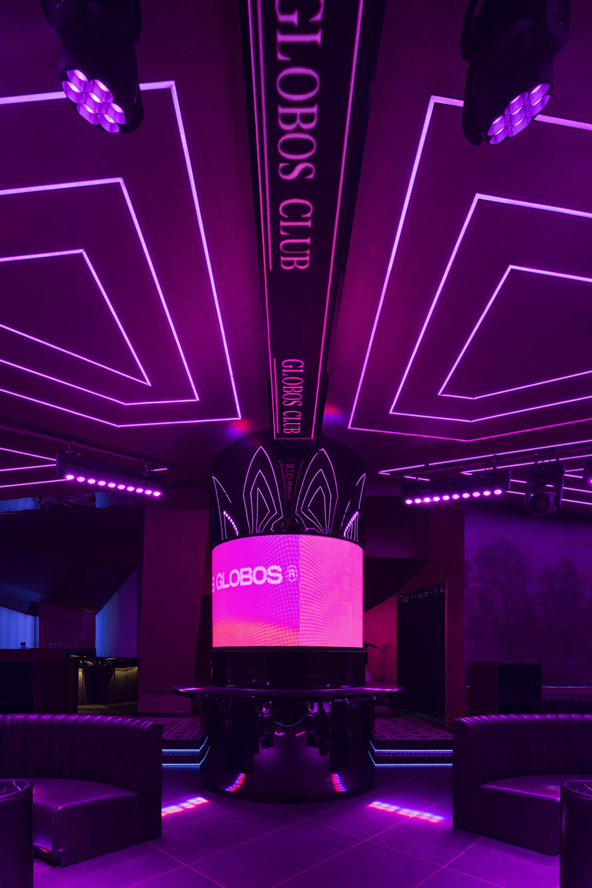 A modern nightclub interior with purple lighting and a central display.