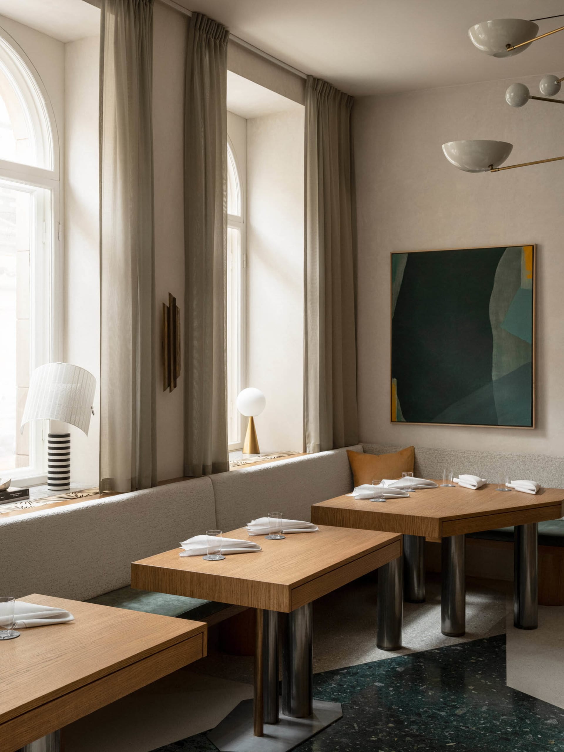 A modern restaurant interior with wooden tables and chairs, adorned with minimalist decor and large windows allowing natural