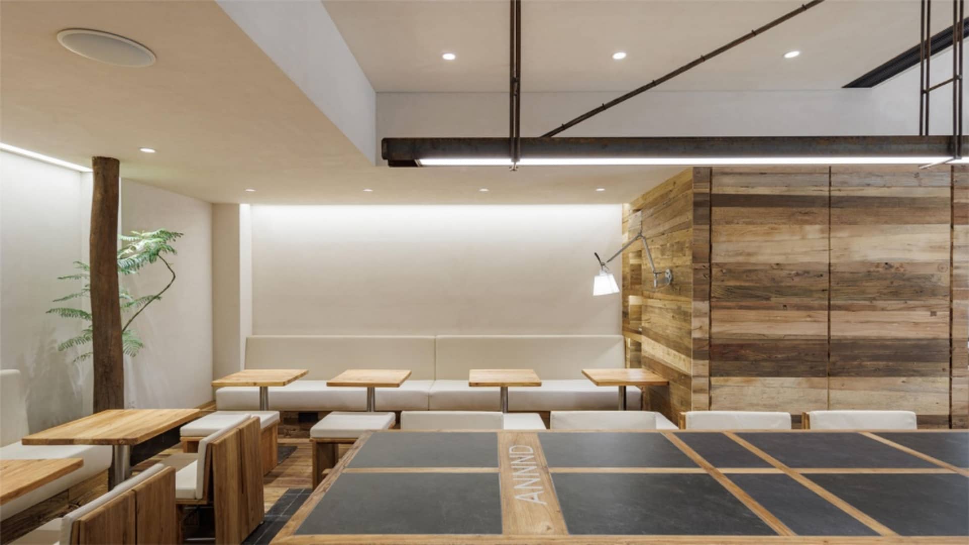 A contemporary restaurant interior with wooden furniture and concrete flooring.
