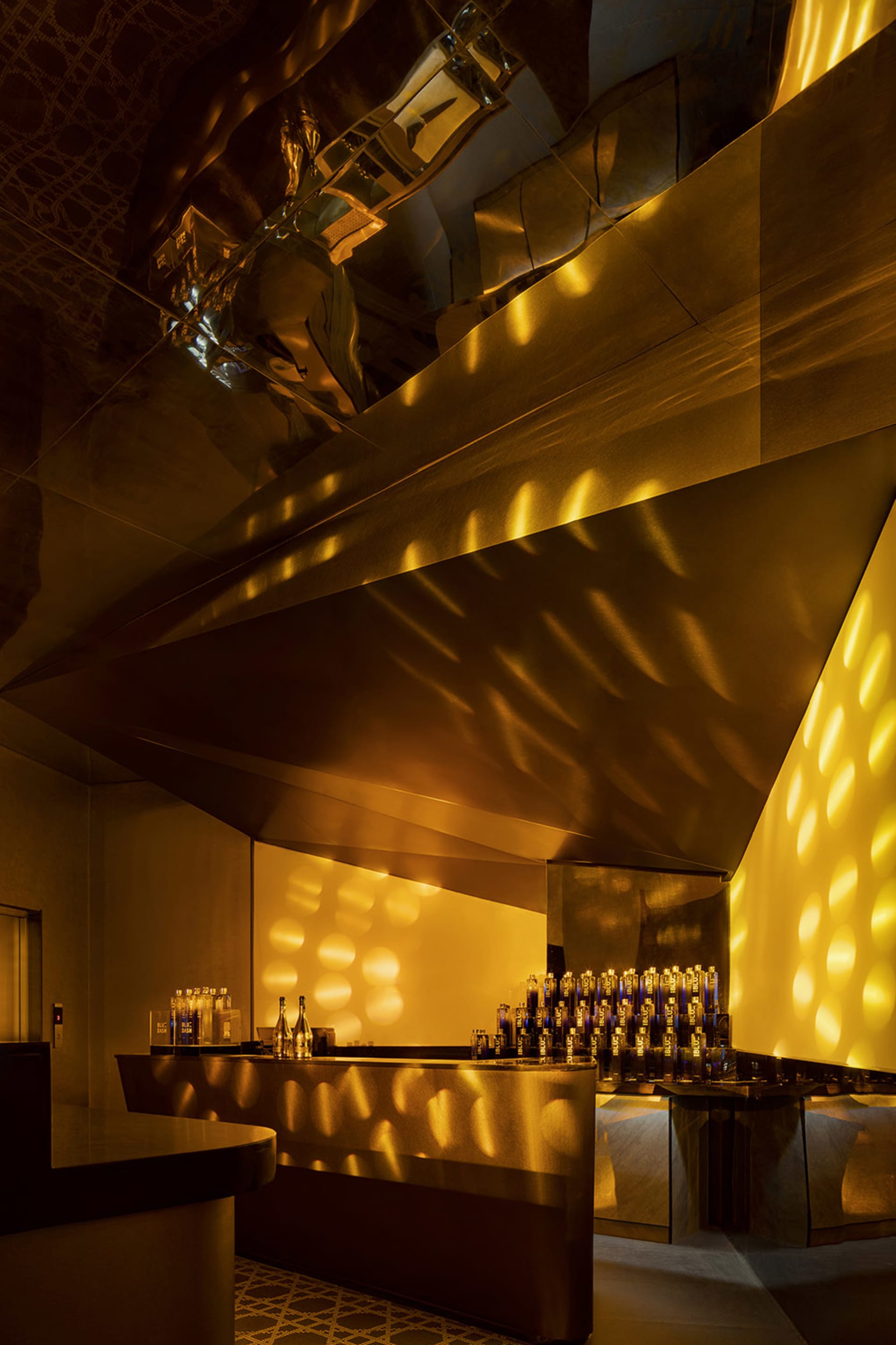 A modern retail bar with a metallic finish, featuring geometric lighting and sleek design elements.