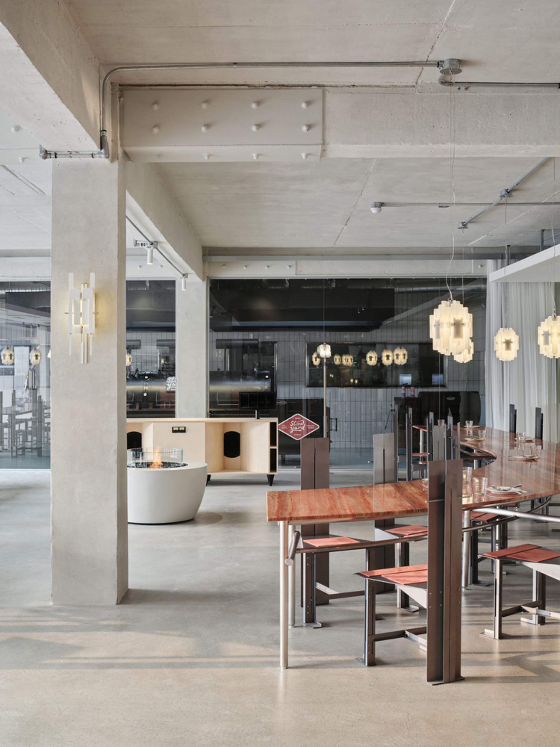 現代簡約咖啡廳室內景觀,混凝土牆面、木質桌檯與吊掛燈具。
