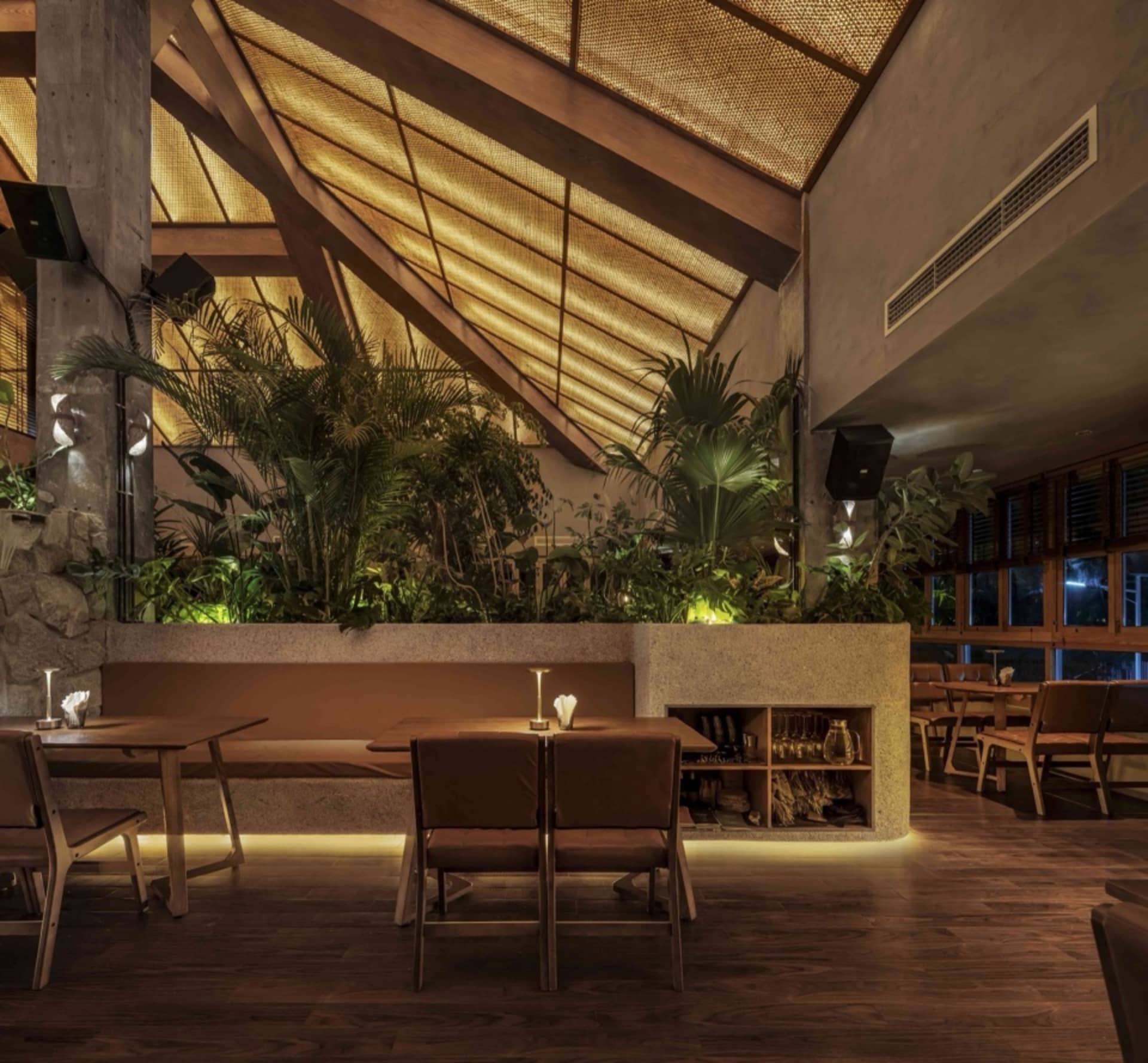 A modern restaurant interior featuring wood, concrete, and plaster materials.