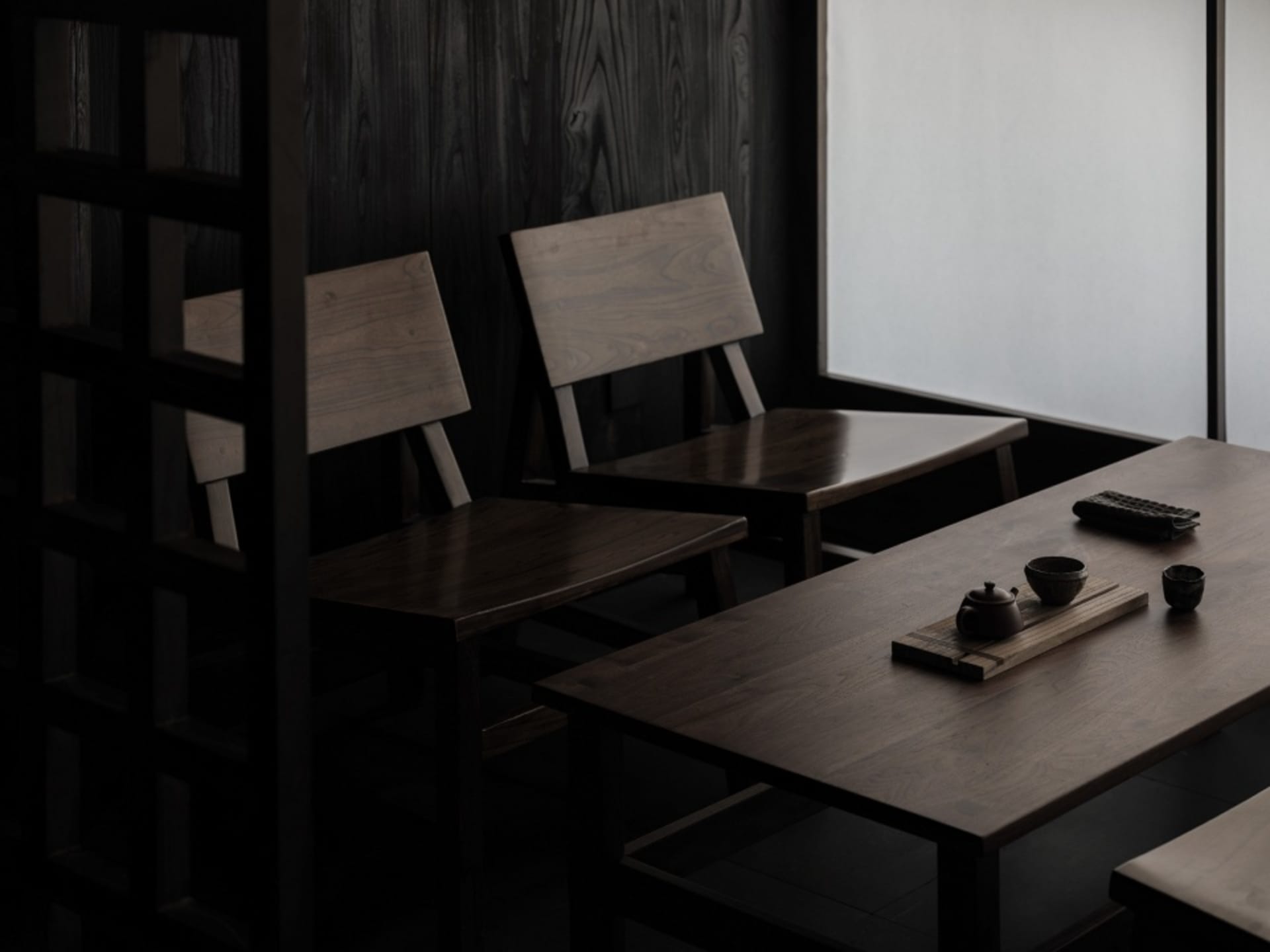 Two wooden tables and chairs in a dimly lit restaurant setting.