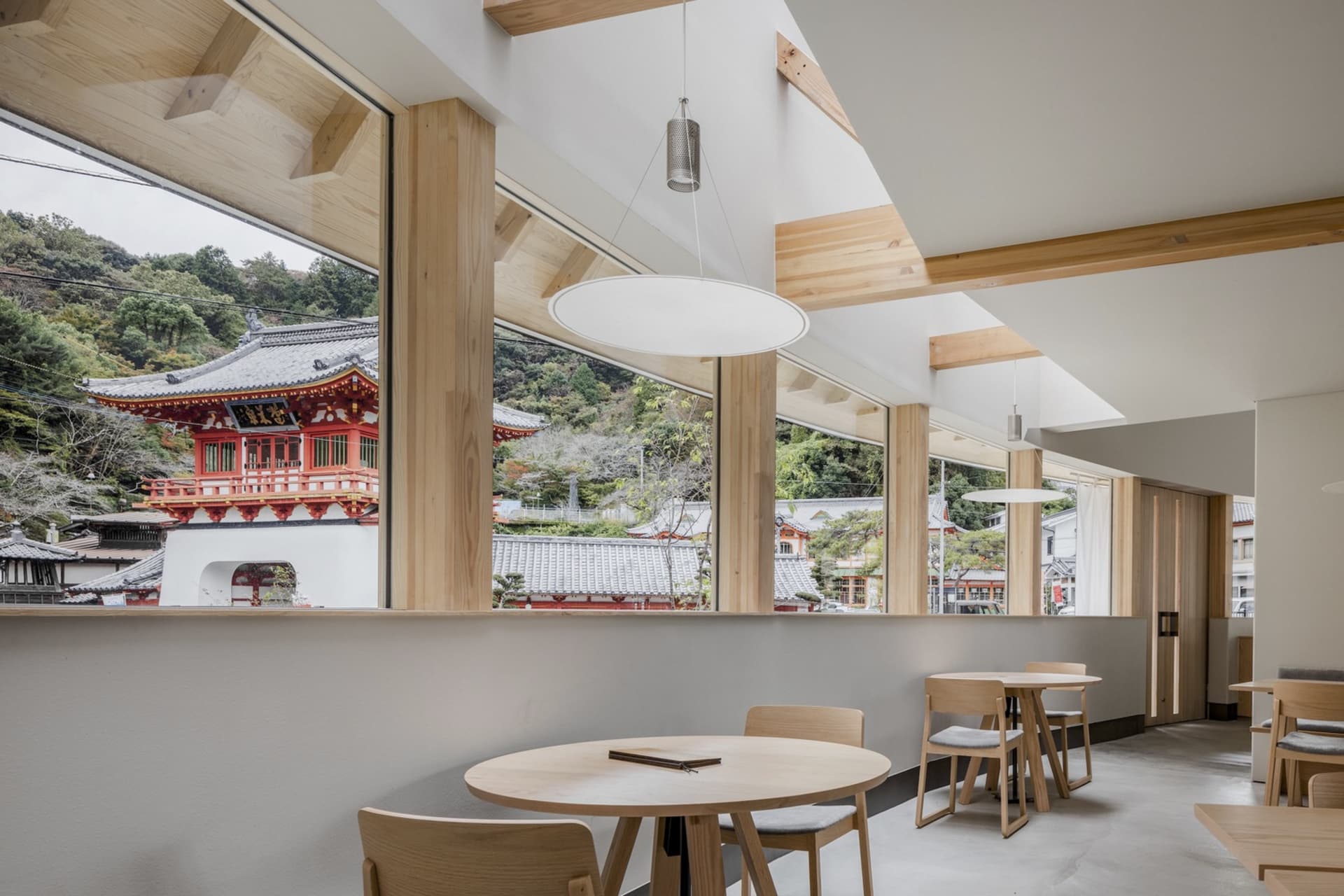 現代咖啡廳室內擺設木質家具與建築細節,窗外可見傳統日式寺廟景觀。
