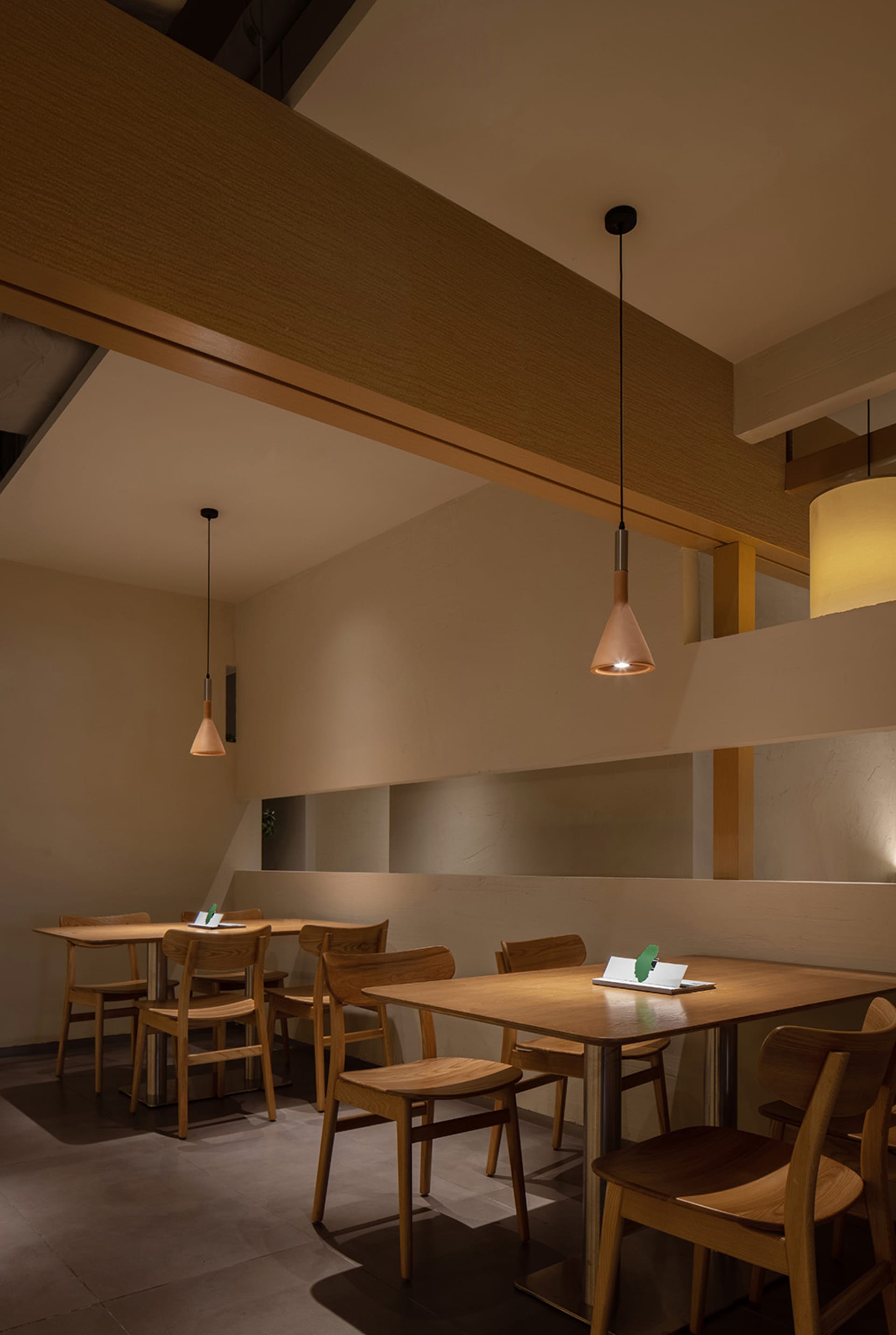 A modern restaurant interior features wooden tables and chairs.
