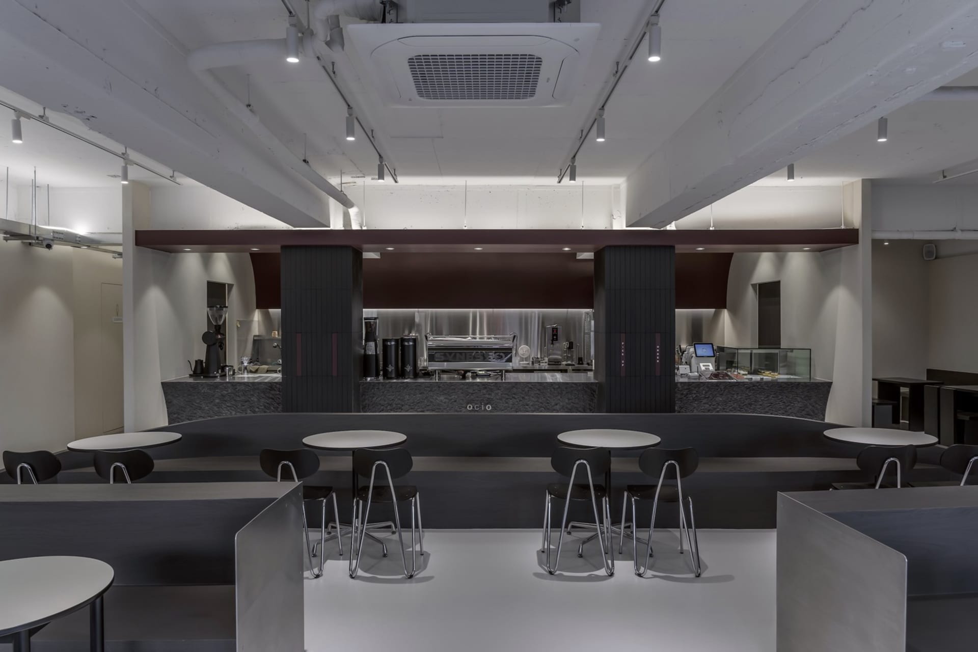 An industrial-style cafe with a metal bar counter and white counter tops.