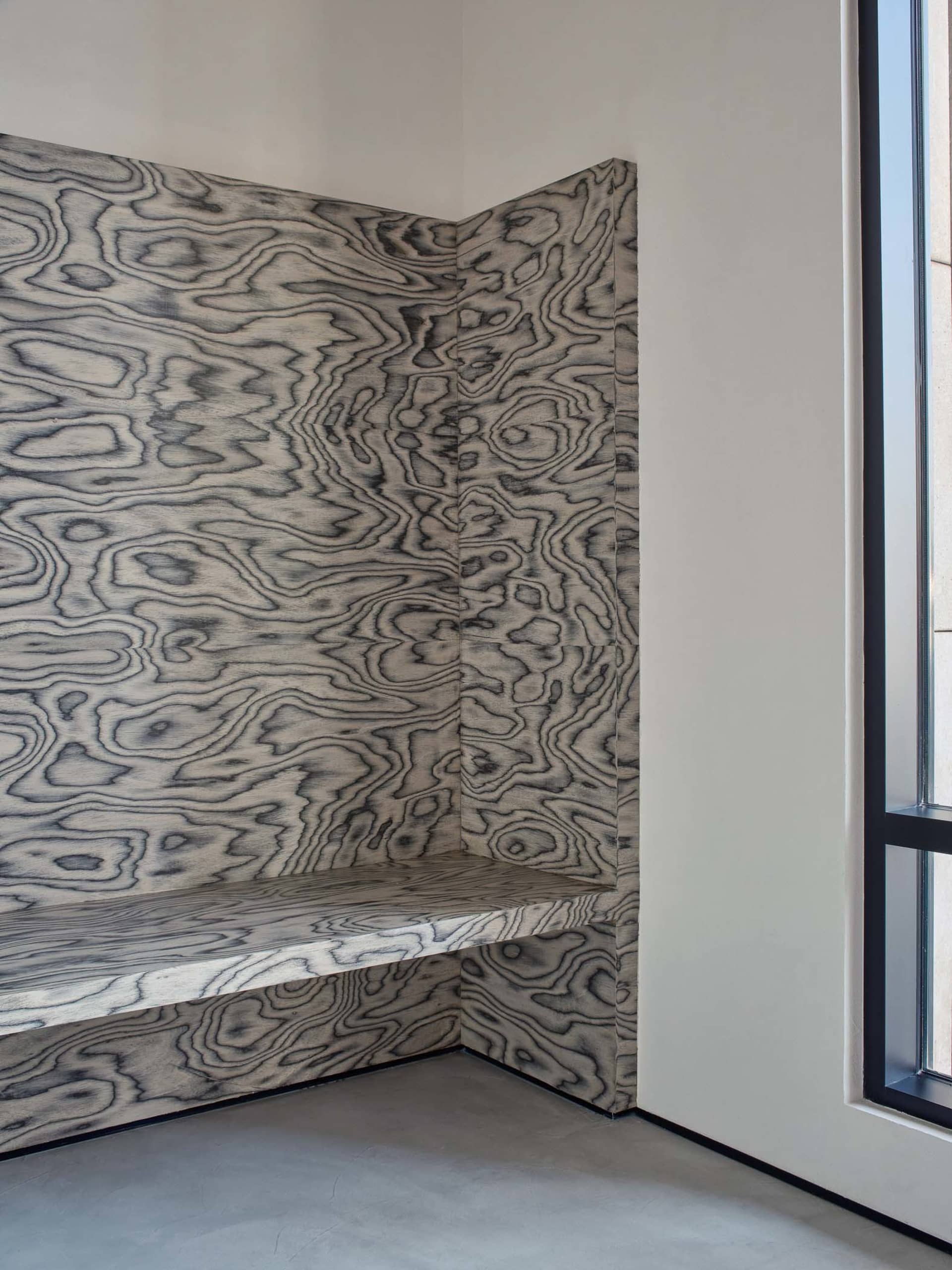 Modern industrial style interior design featuring a corner bench with a wood-patterned panel