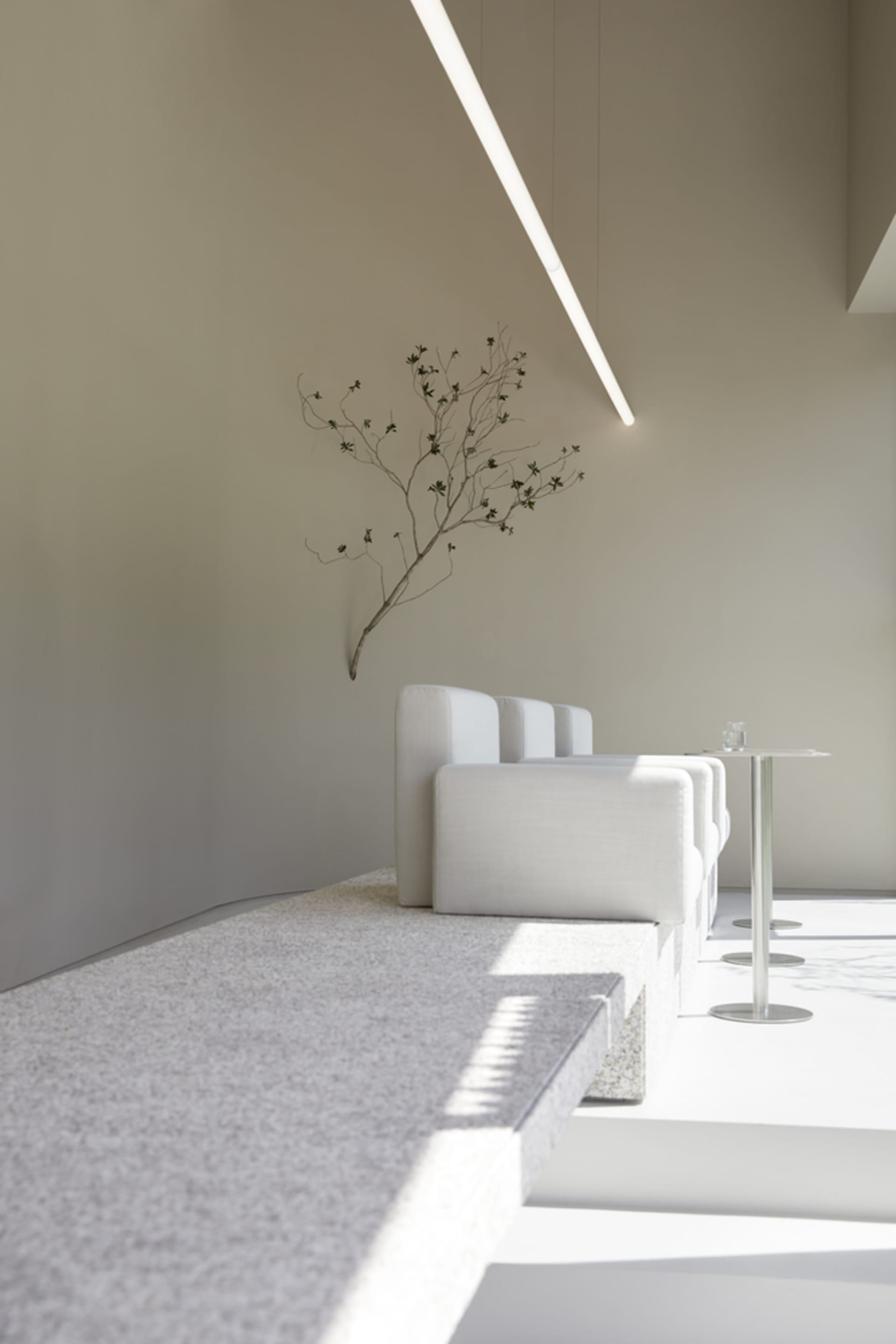 Minimalist waiting area with terrazzo flooring and white furniture.