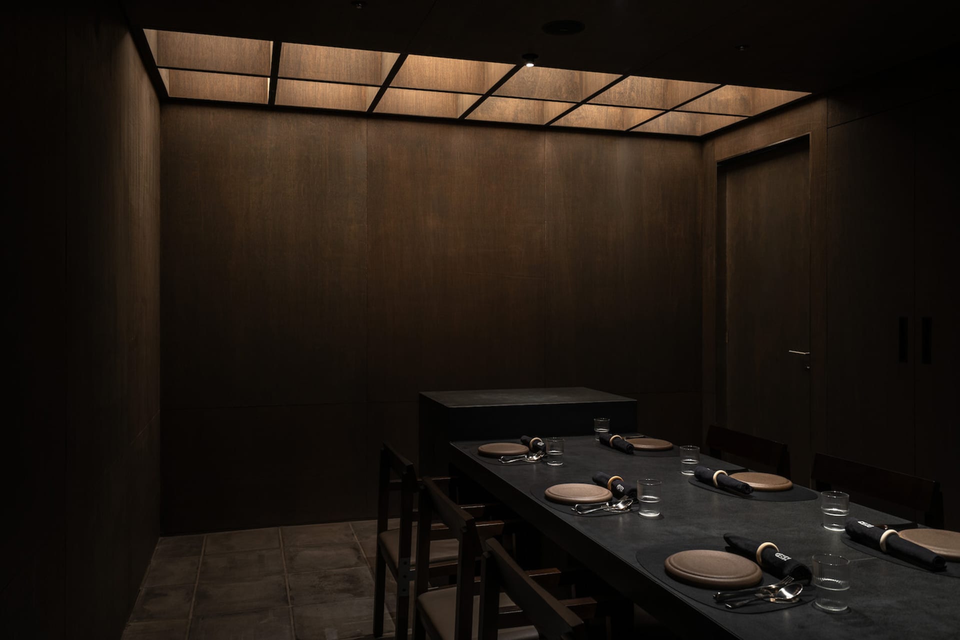 A modern private dining room with wood paneling and a large table.