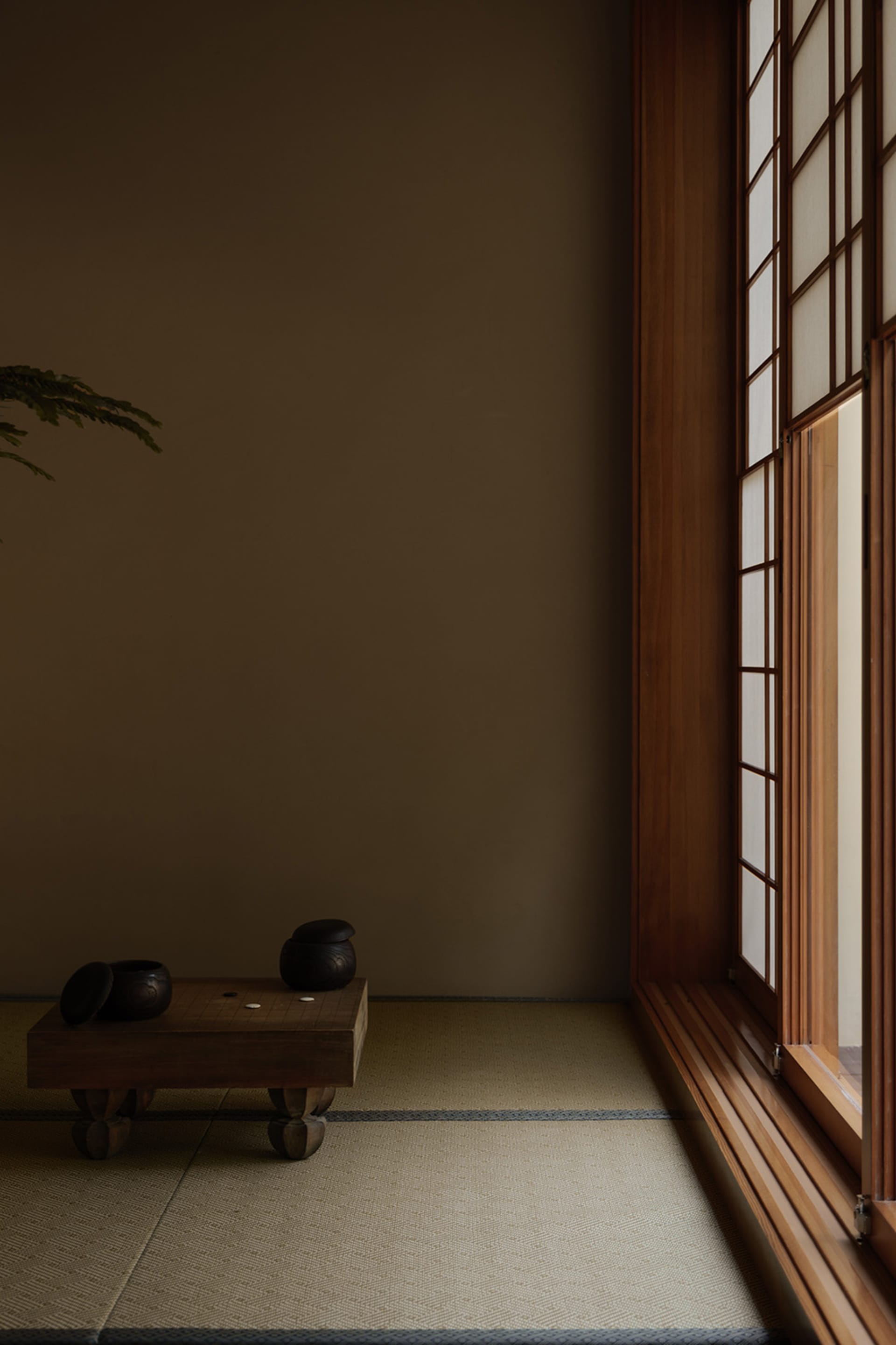 A serene Japanese tea room with a tatami mat floor, minimalist decor, and a window on the right.