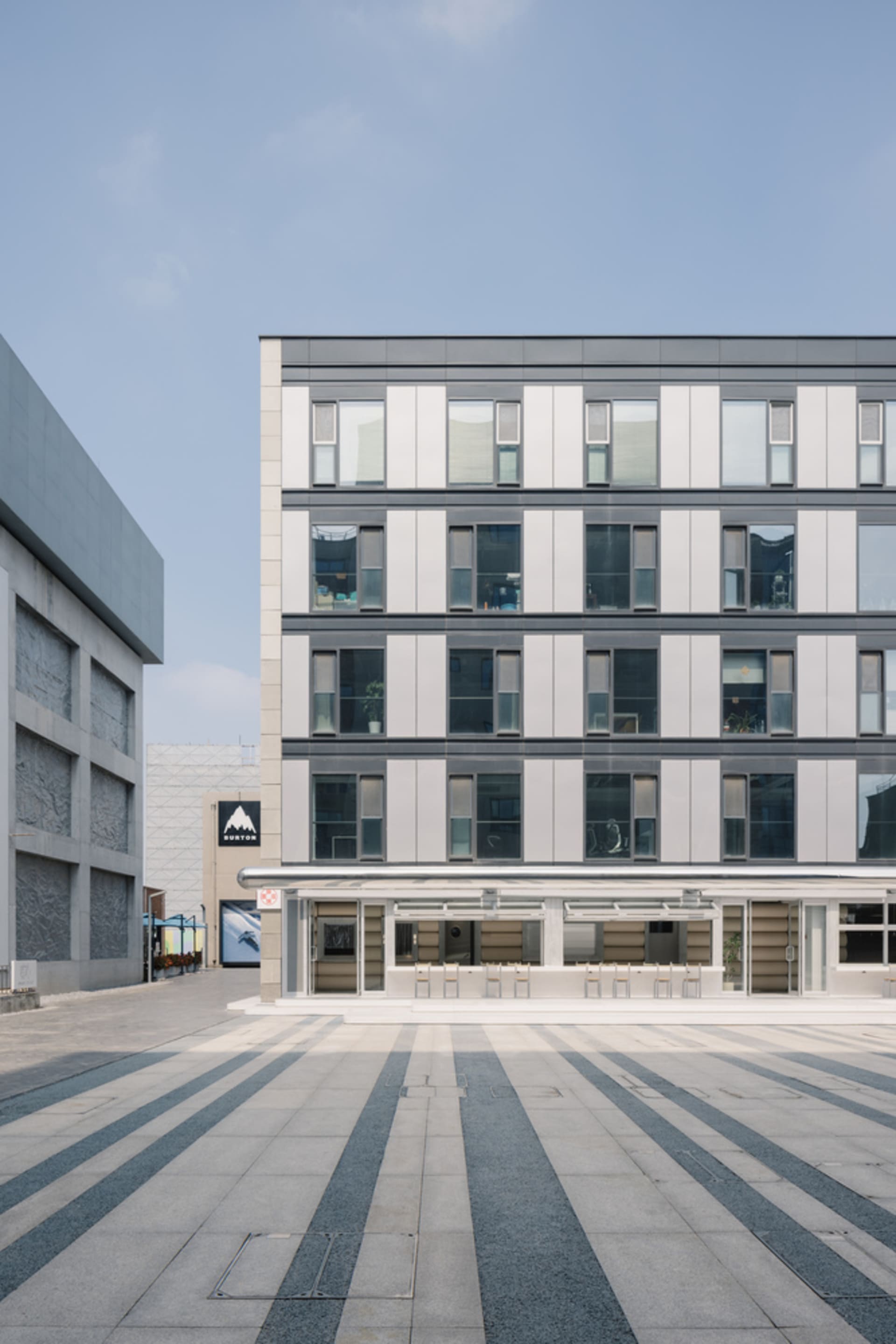 A contemporary modern building constructed with concrete and featuring geometric patterns on its facade and floor.