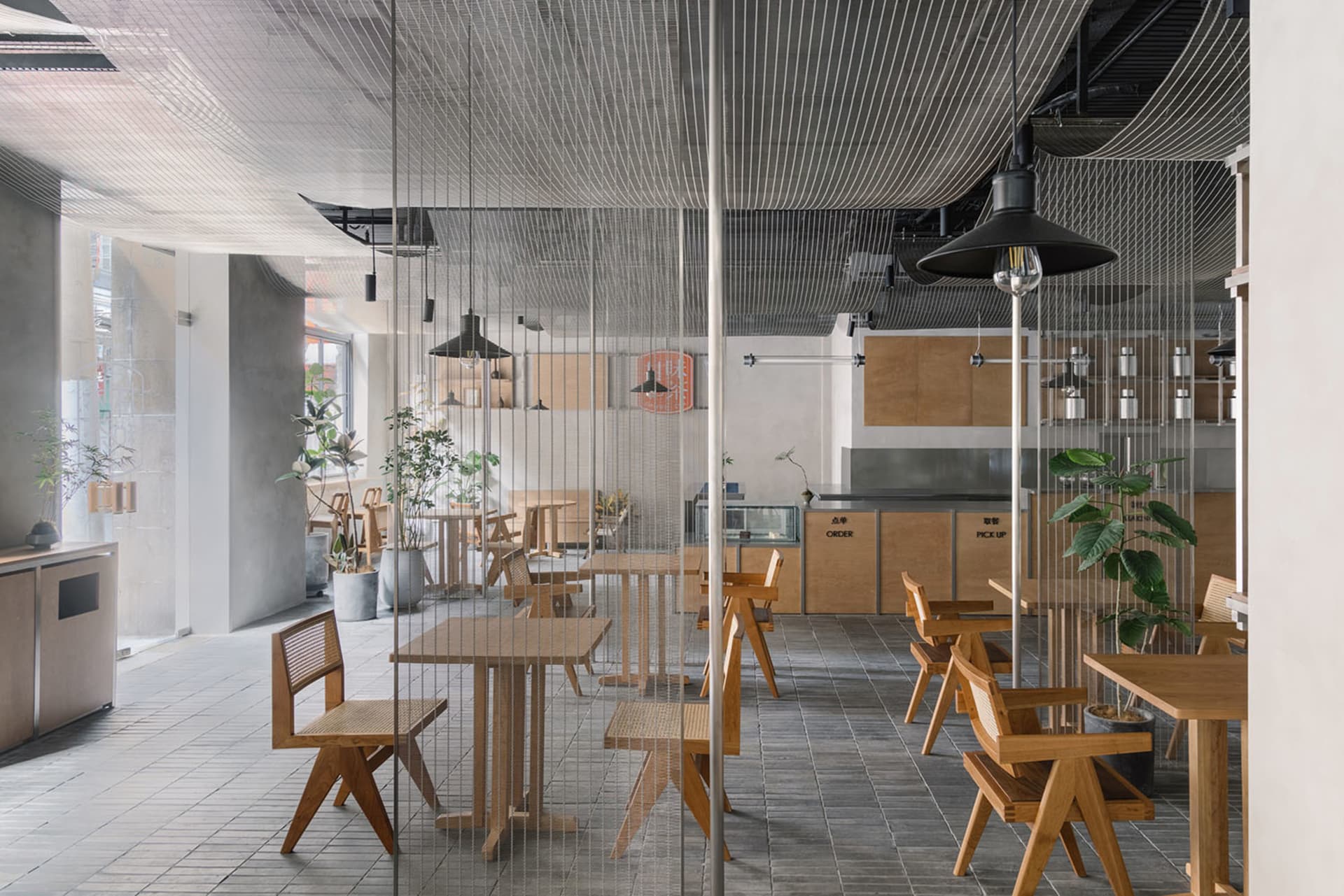現代餐廳室內,展示木質桌椅、混凝土地板與工業風燈具。