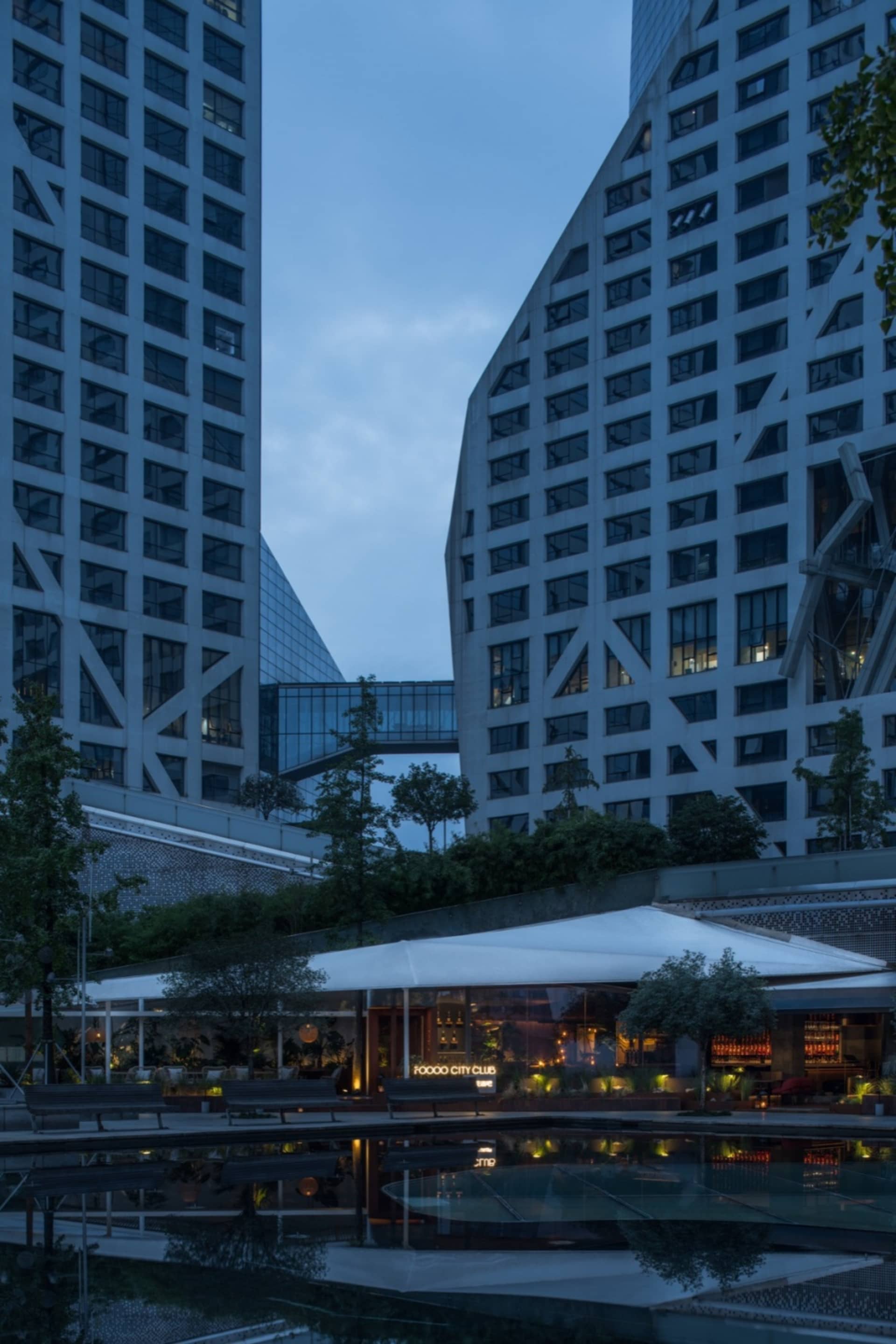 高樓大廈在黃昏時分被燈光照亮,擁有玻璃外牆與都市景觀。