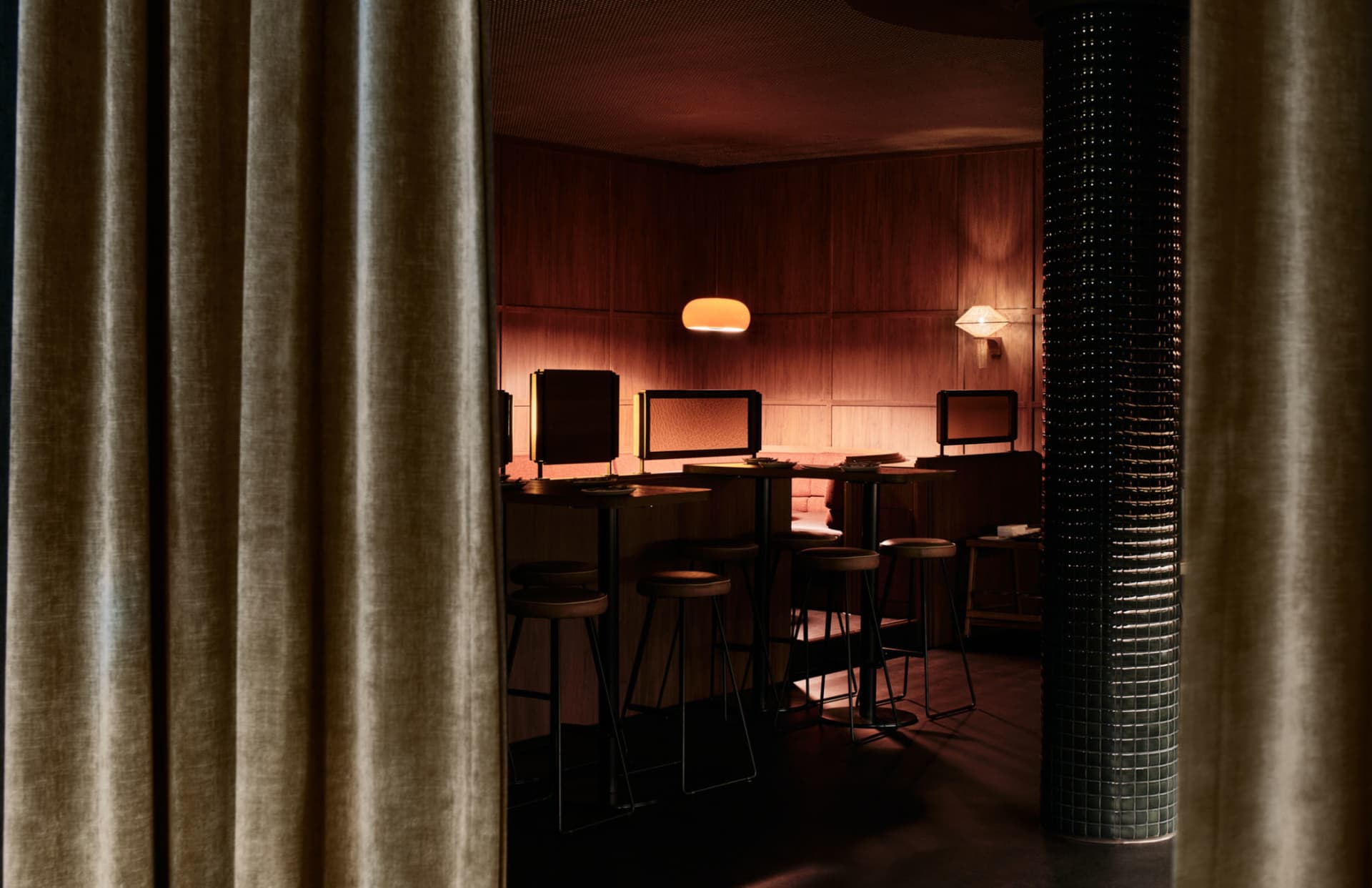 A cozy industrial-style bar interior featuring leather seating and illuminated by warm lights.