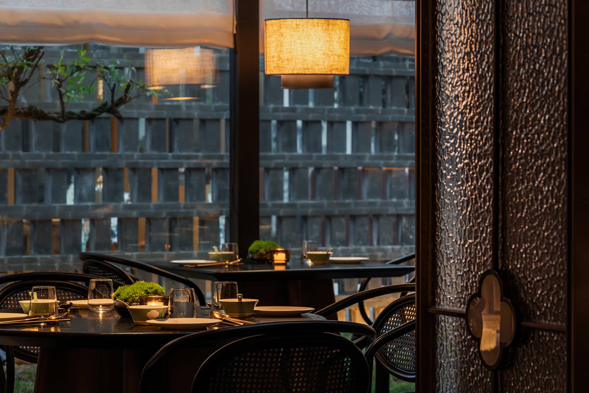 Modern restaurant interior with wooden tables, glass lamps, and fabric pendant lights.