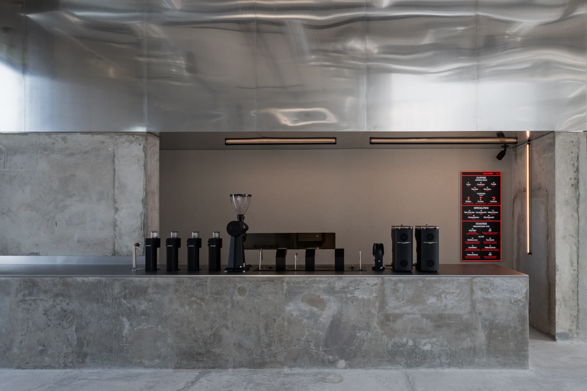 Modern, minimalist coffee shop counter with concrete finish and sleek design.