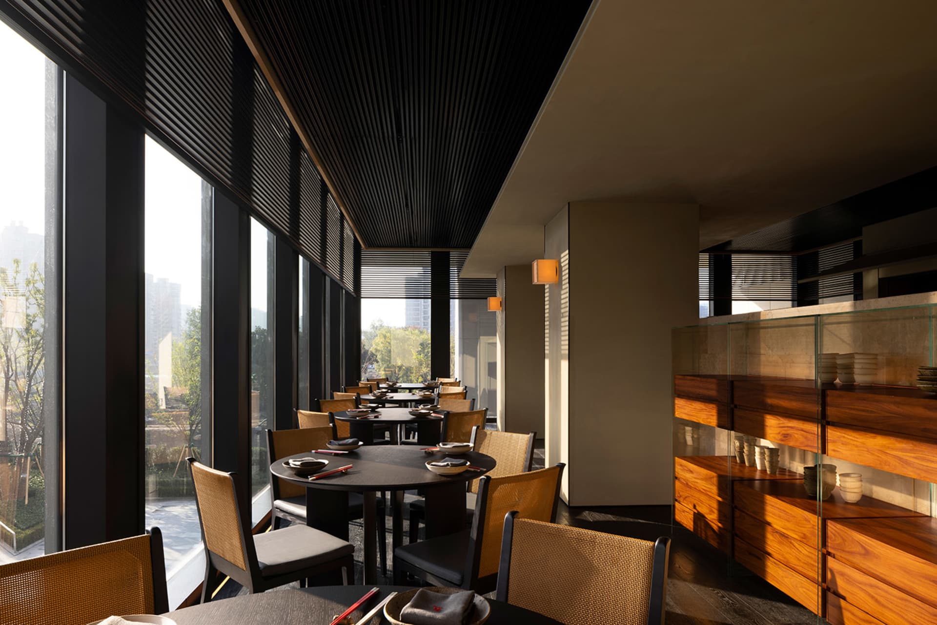A modern industrial restaurant dining area with neutral-toned materials and large windows.