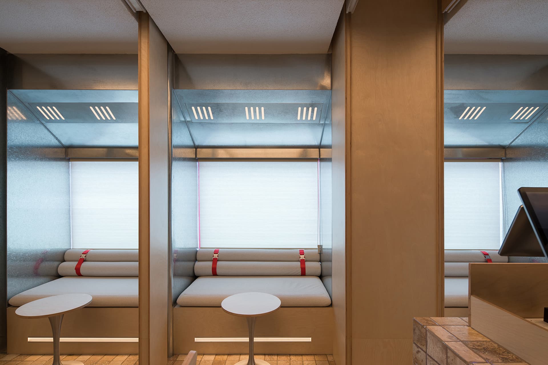 Modern minimalist restaurant booths constructed from wood and a plastic composite material, providing a comfortable seating a
