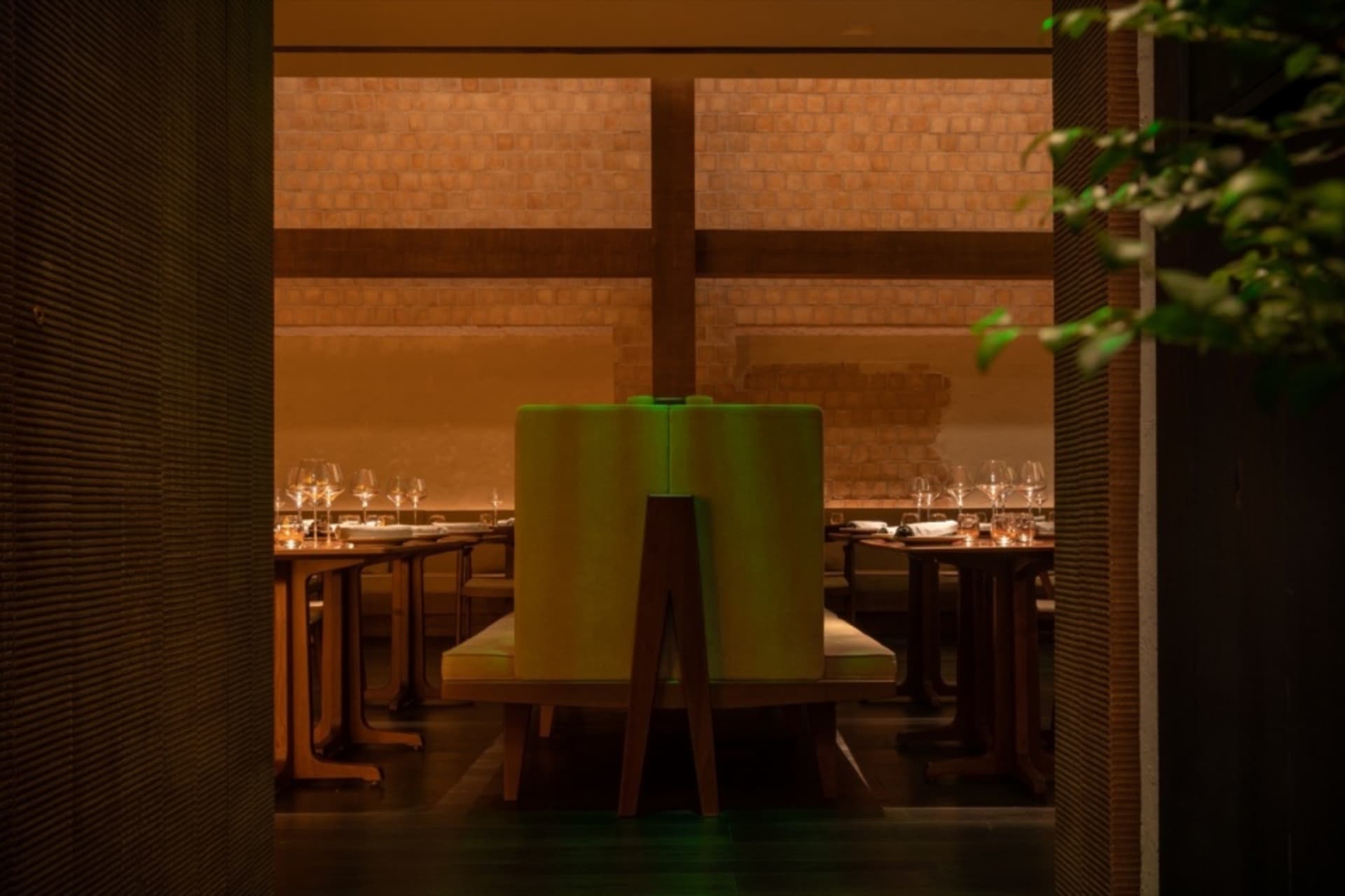 現代餐廳用餐區，配有綠色餐椅與木質餐桌，柔和燈光照亮空間，四周環繞綠意植物。