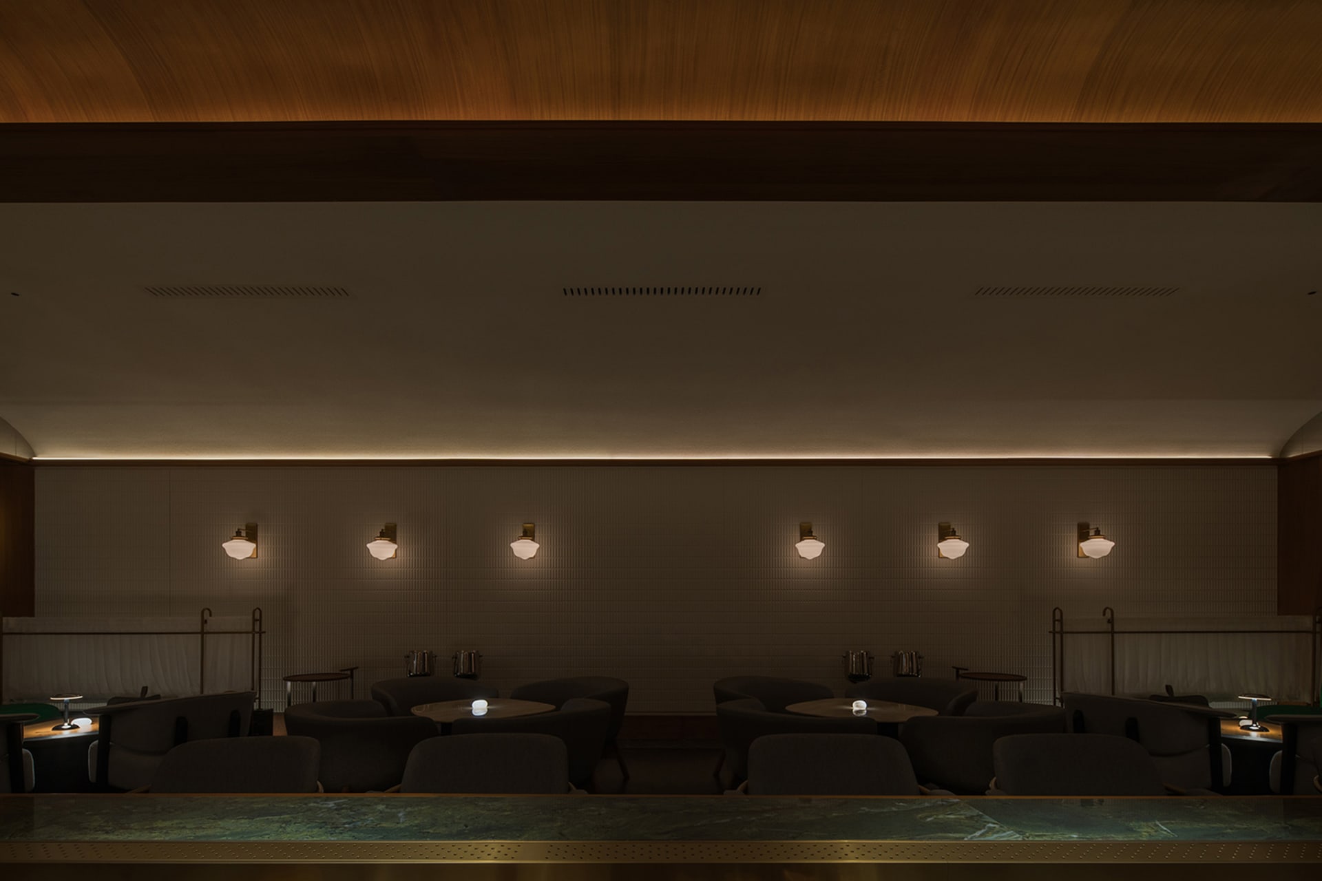 現代餐廳吧台，搭配混凝土牆面與燈具照明。