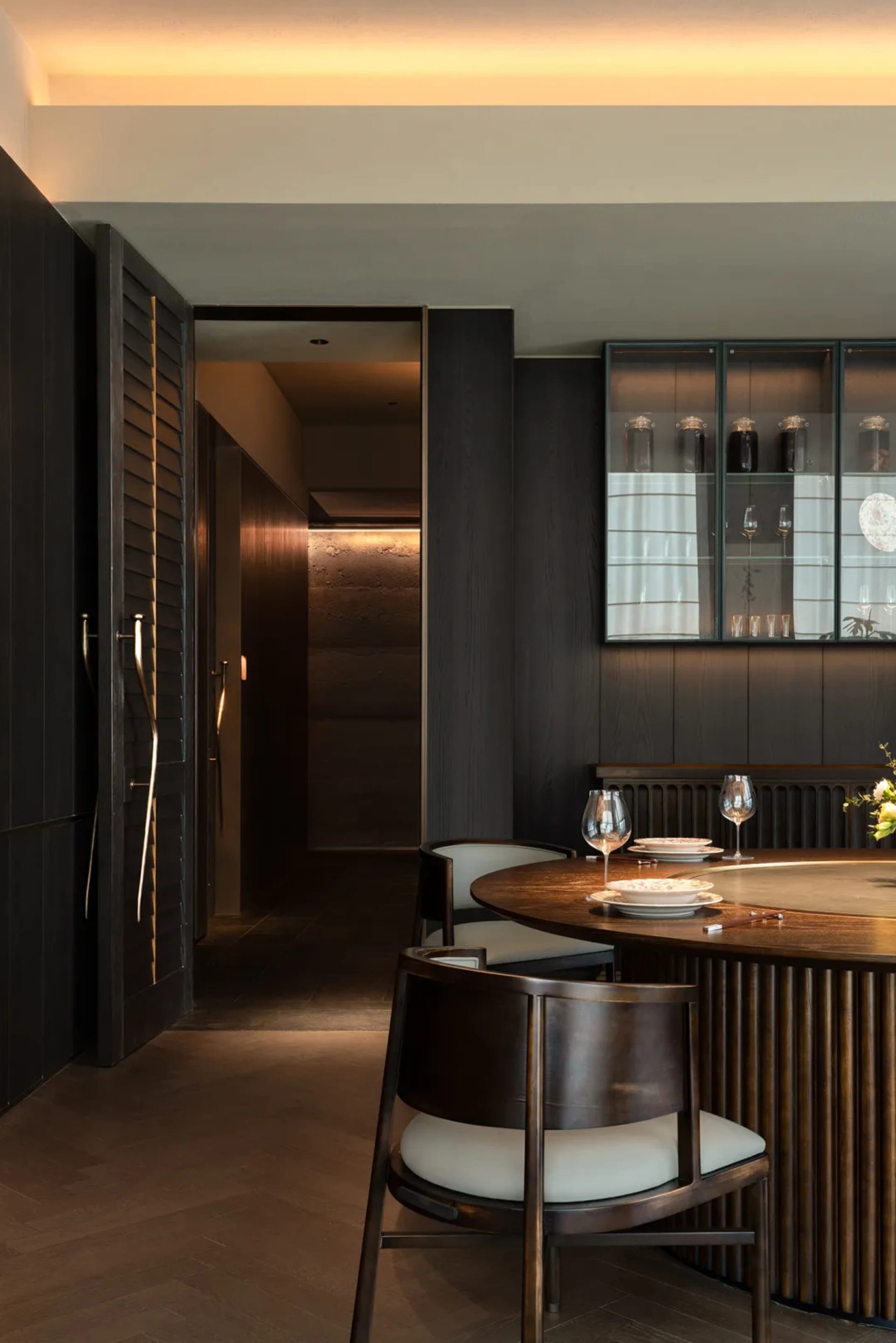 Modern dining room with walnut wood furniture and dark wooden paneling.